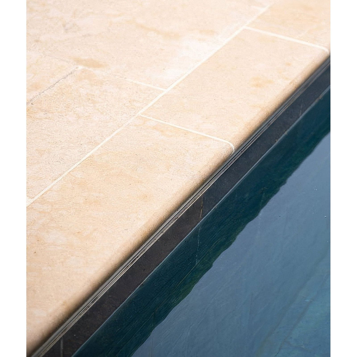 Beige buscot limestone etched bullnose coping with sleek black metal edge trim for stone pool coping