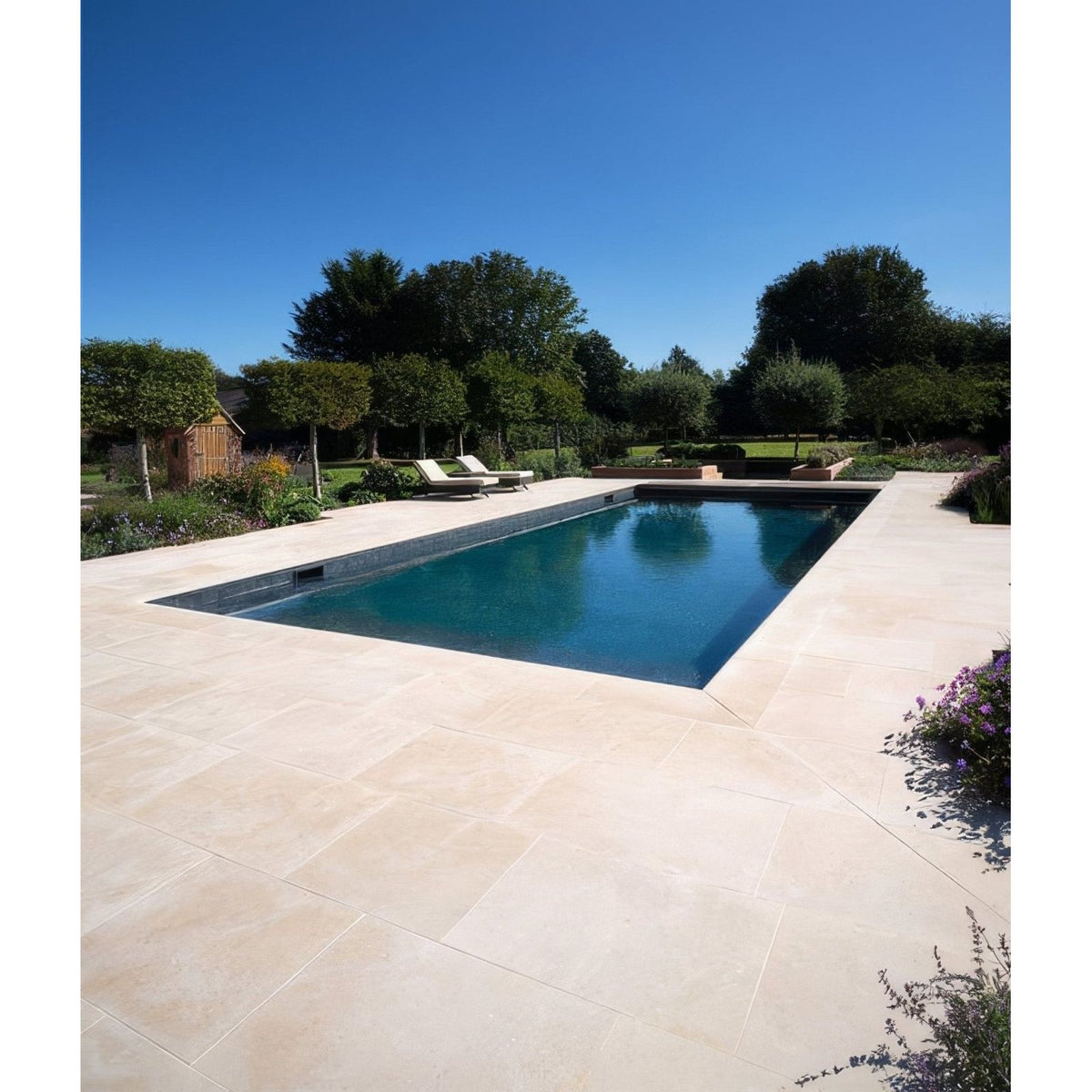 Rectangular buscot limestone paving with etched finish in light beige surrounding clear blue pool water