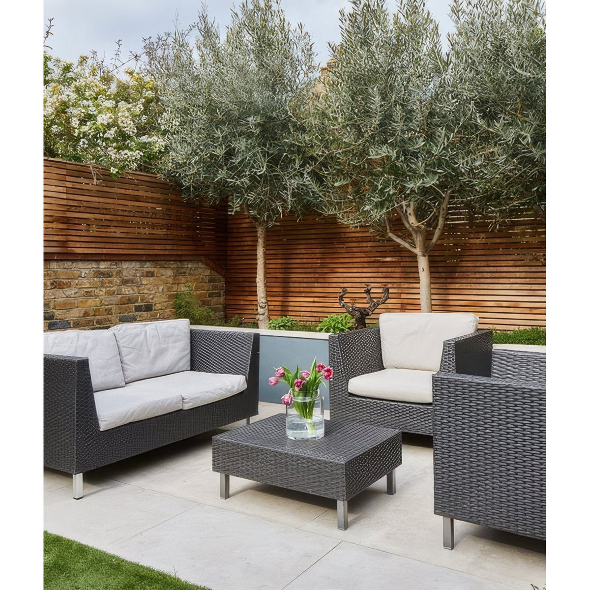 Dark gray woven wicker patio set with white cushions on buscot limestone paving etched finish