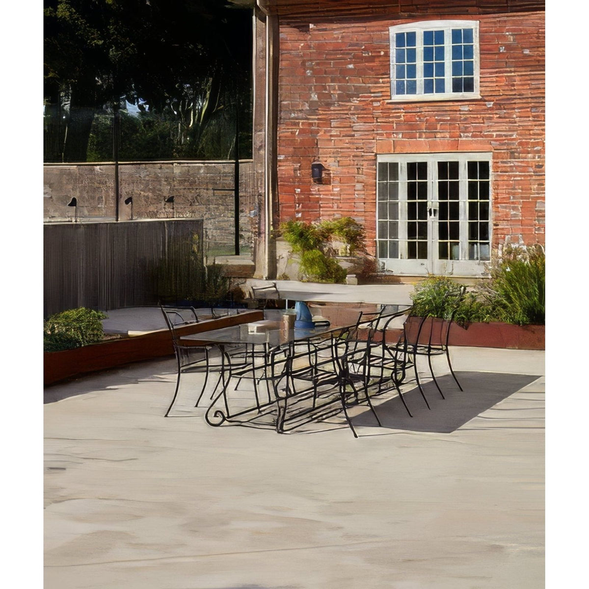 Black wrought iron patio dining set with glass top table and matching chairs on buscot limestone paving tumbled and etched finish
