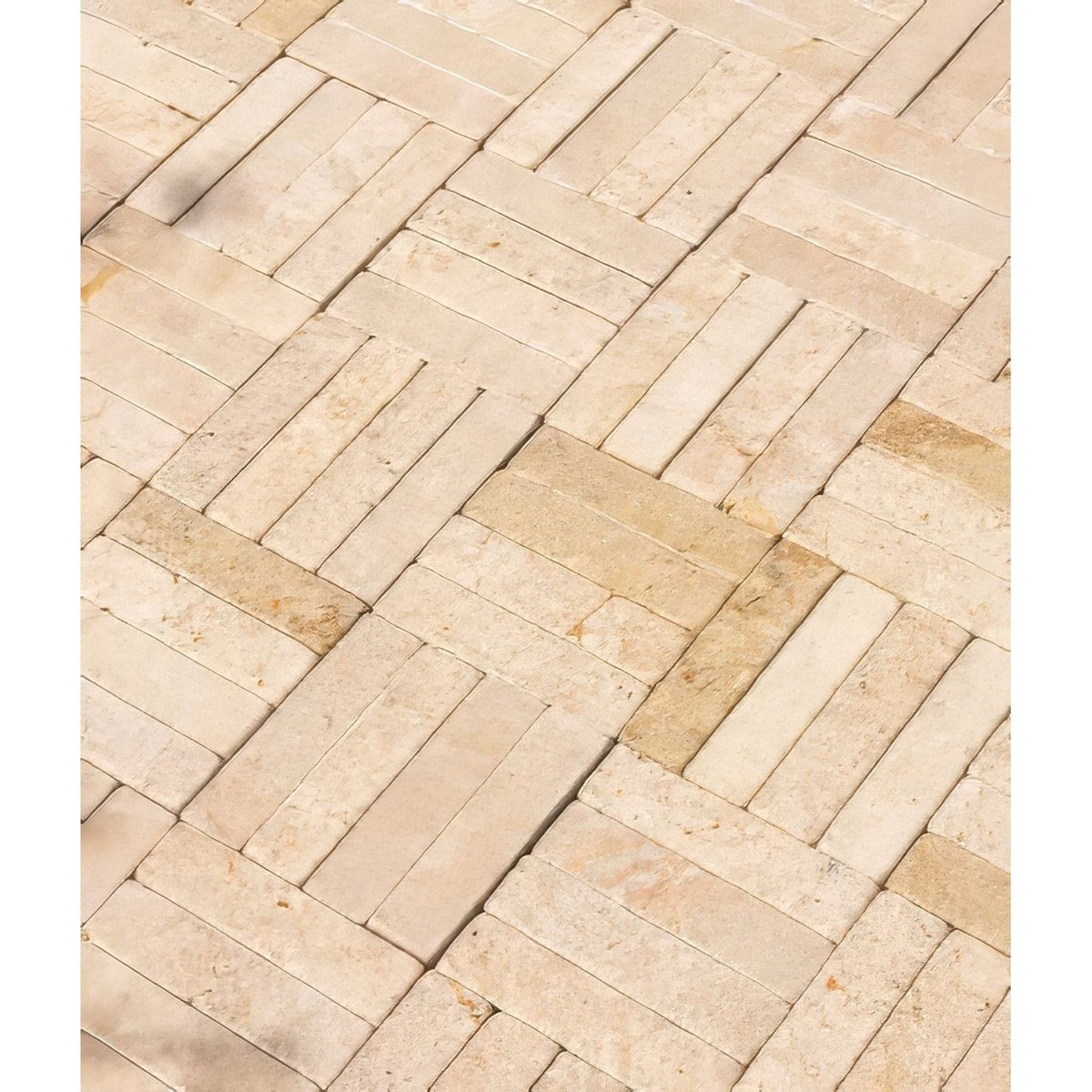 Beige and cream-colored buscot limestone tumbled and etched klinkers arranged in a rectangular herringbone pattern