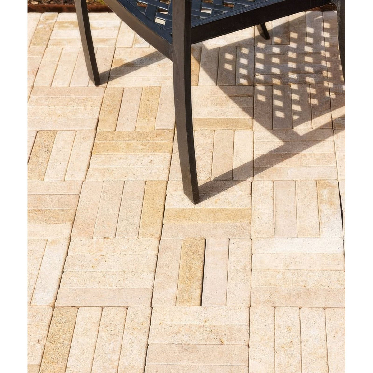 Beige and cream-colored buscot limestone tumbled and etched klinkers stone pavers arranged in a herringbone pattern
