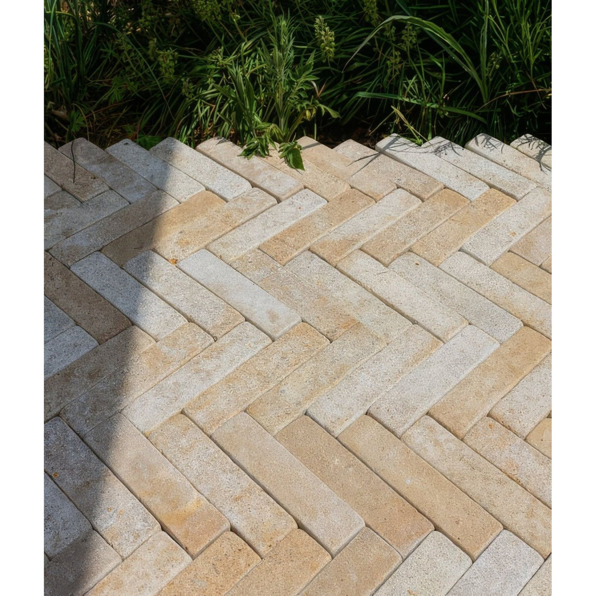 Beige and gray herringbone patterned buscot limestone tumbled and etched stone pavers for outdoor use