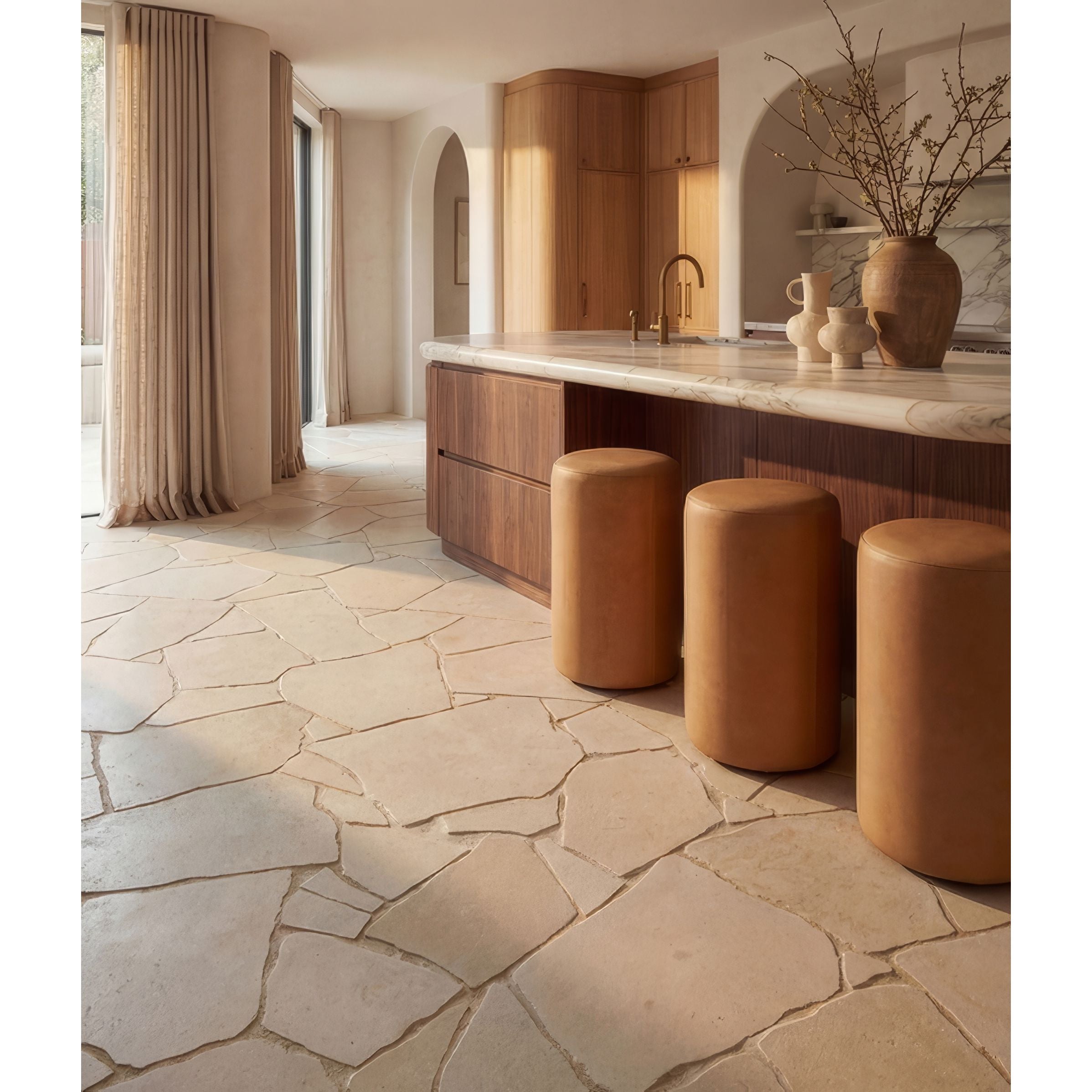 Modern kitchen with stone flooring, wooden cabinets, and leather stools.