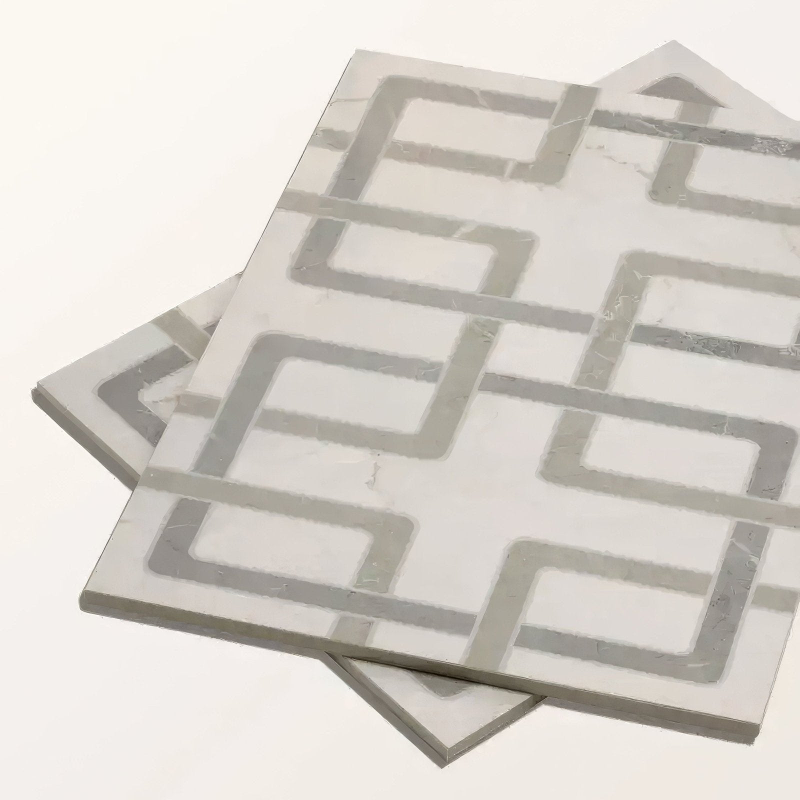 Gray and white geometric patterned mosaic tiles with a marble-like finish.