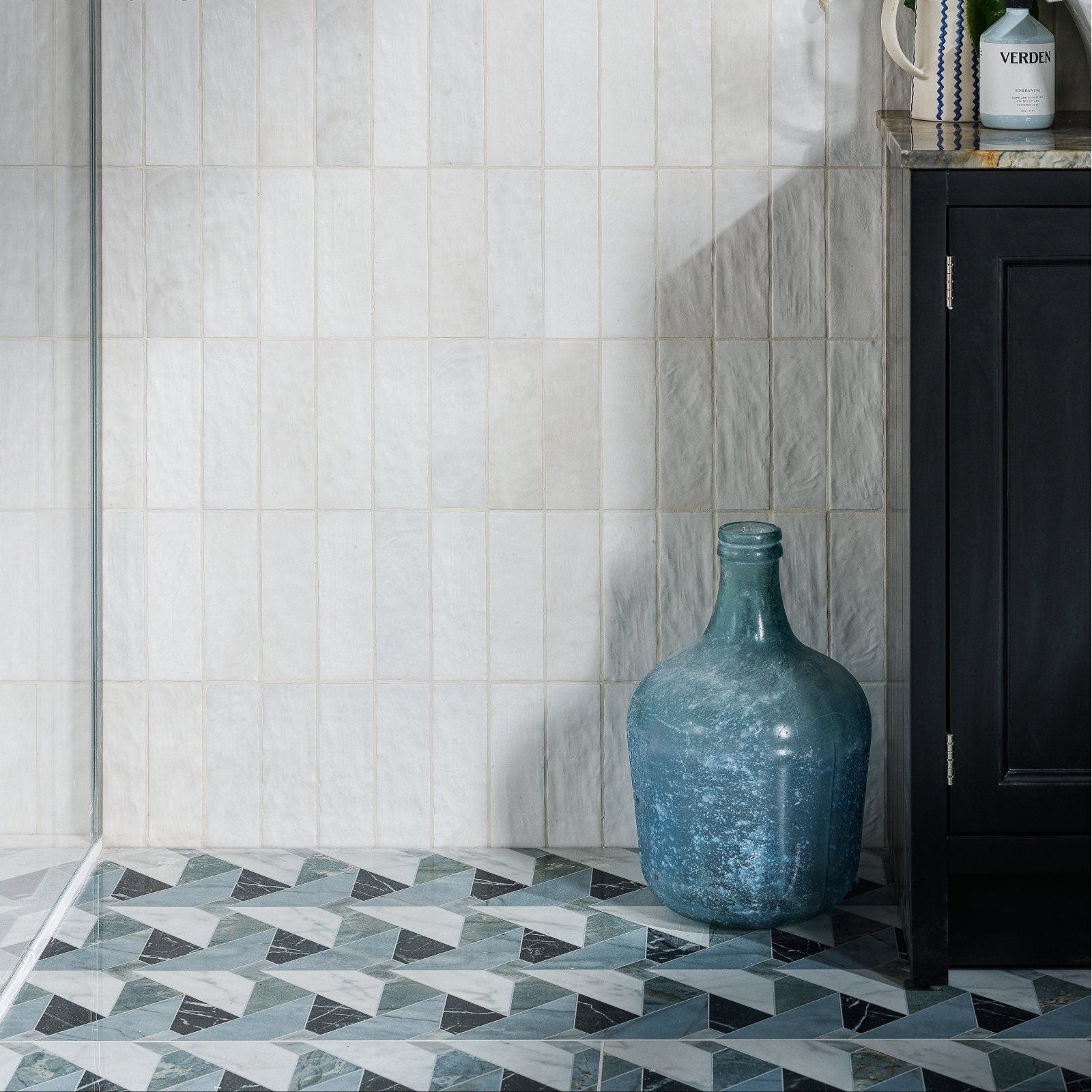 Byzantine Porcelain Seraph Sculpted geometric marble-effect porcelain tiles styled with a matte teal glass bottle