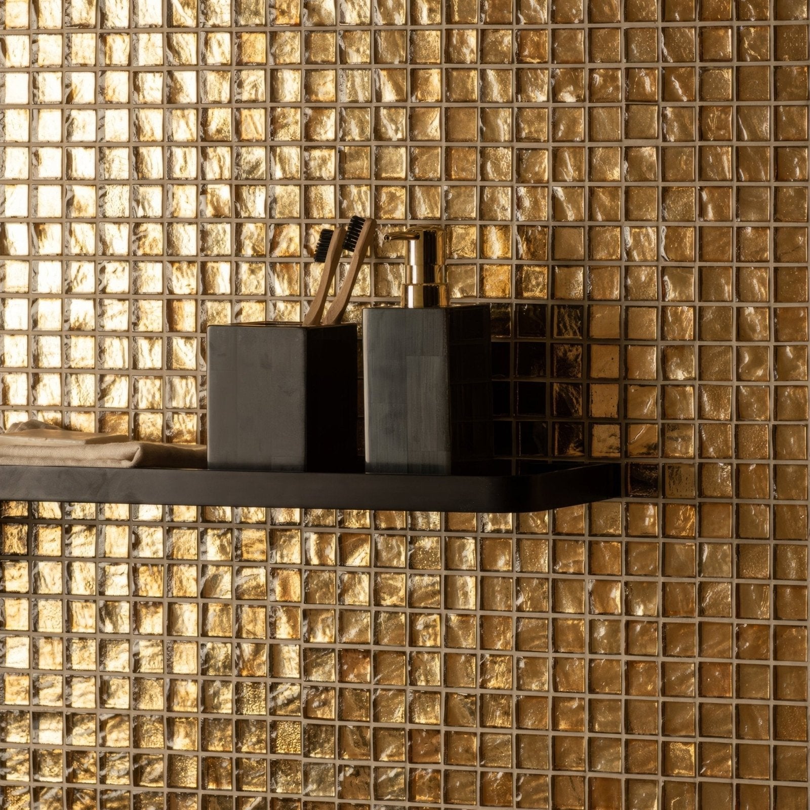 Byzantium Gold Glass Mosaic gold glass mosaic wall with a black soap dispenser on a shelf