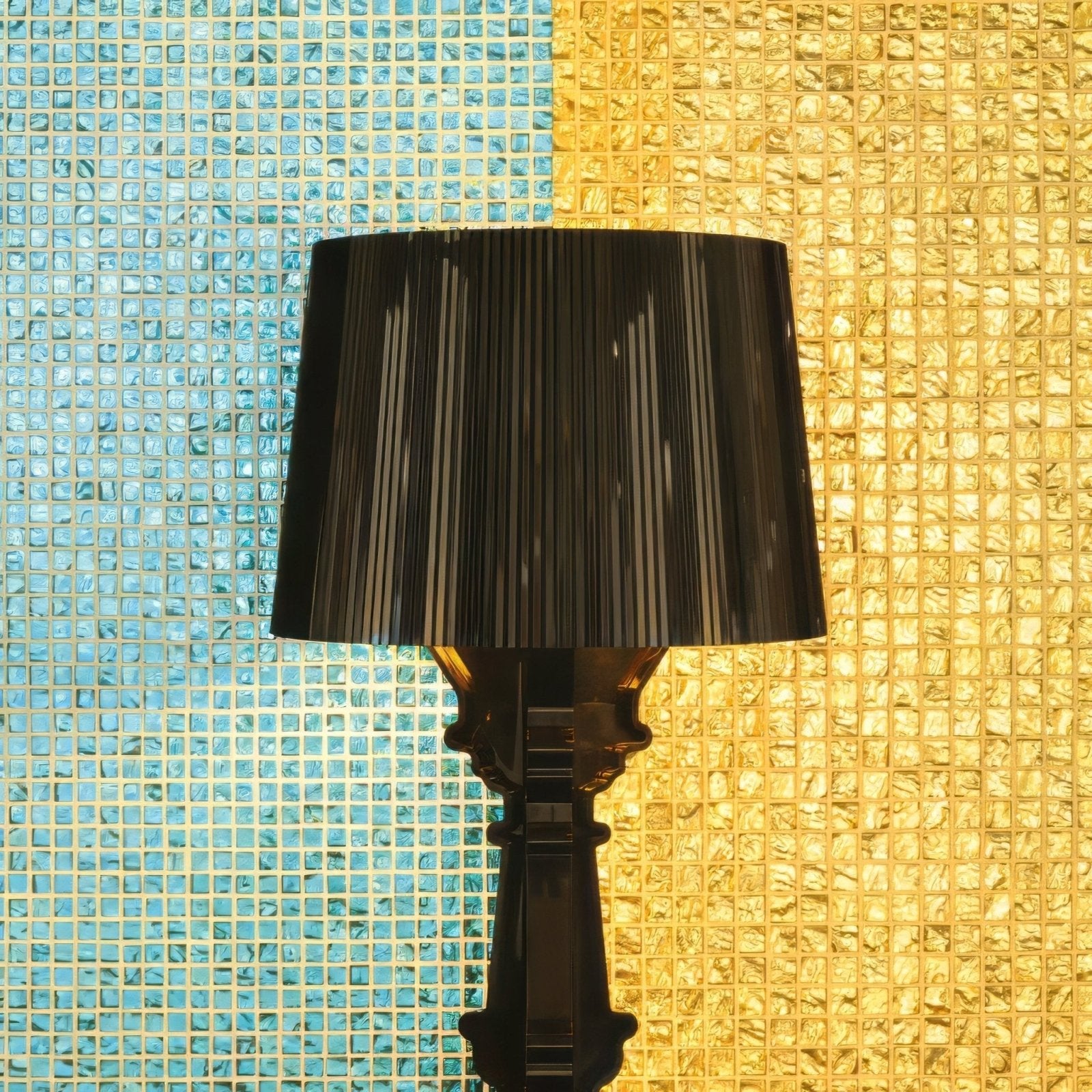 Black pleated lampshade with a glossy sculpted base against Byzantium treasure glass mosaic tile wall