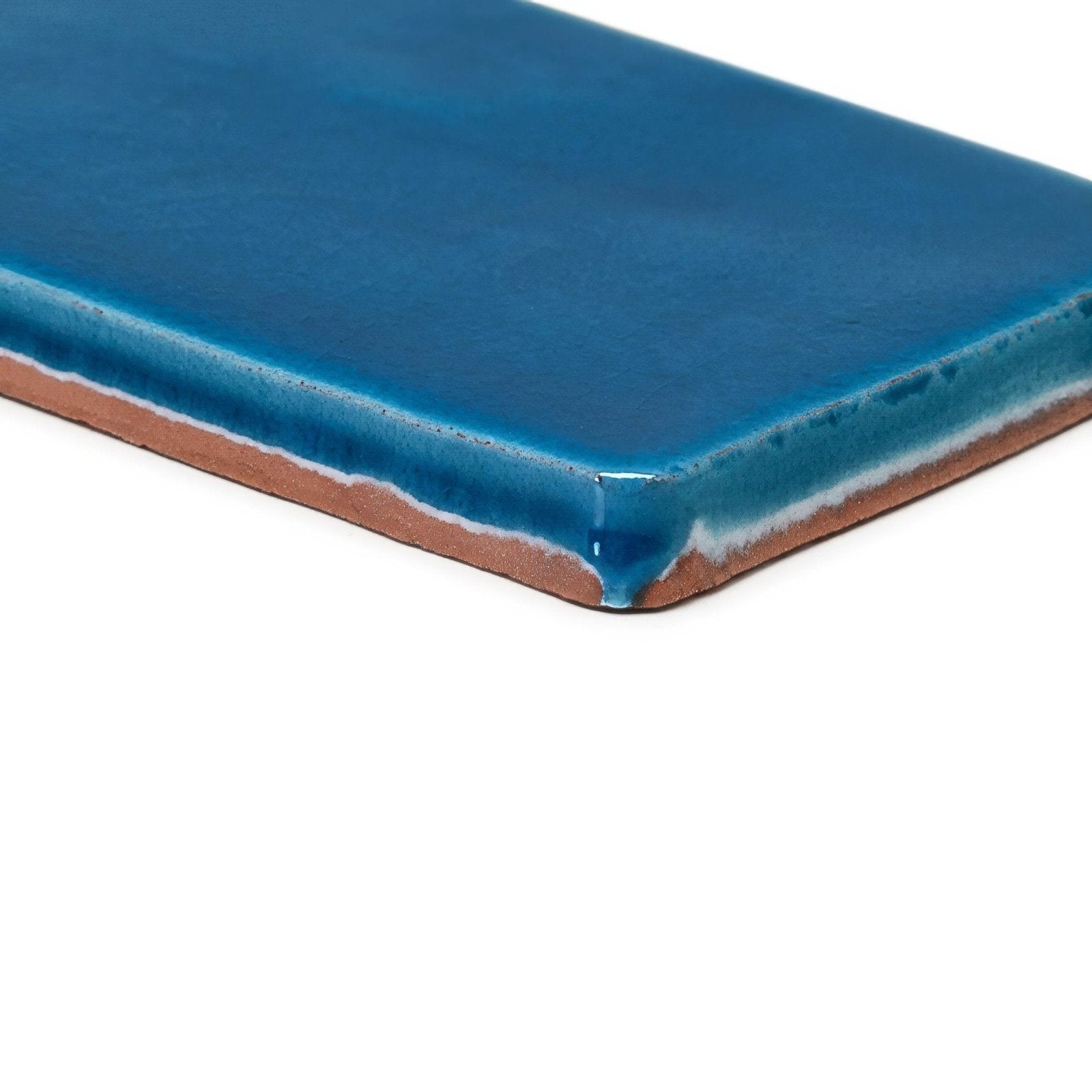 A rectangular ceramic carnival pancho blue glazed tile with glossy cobalt blue surface and visible terracotta clay edges