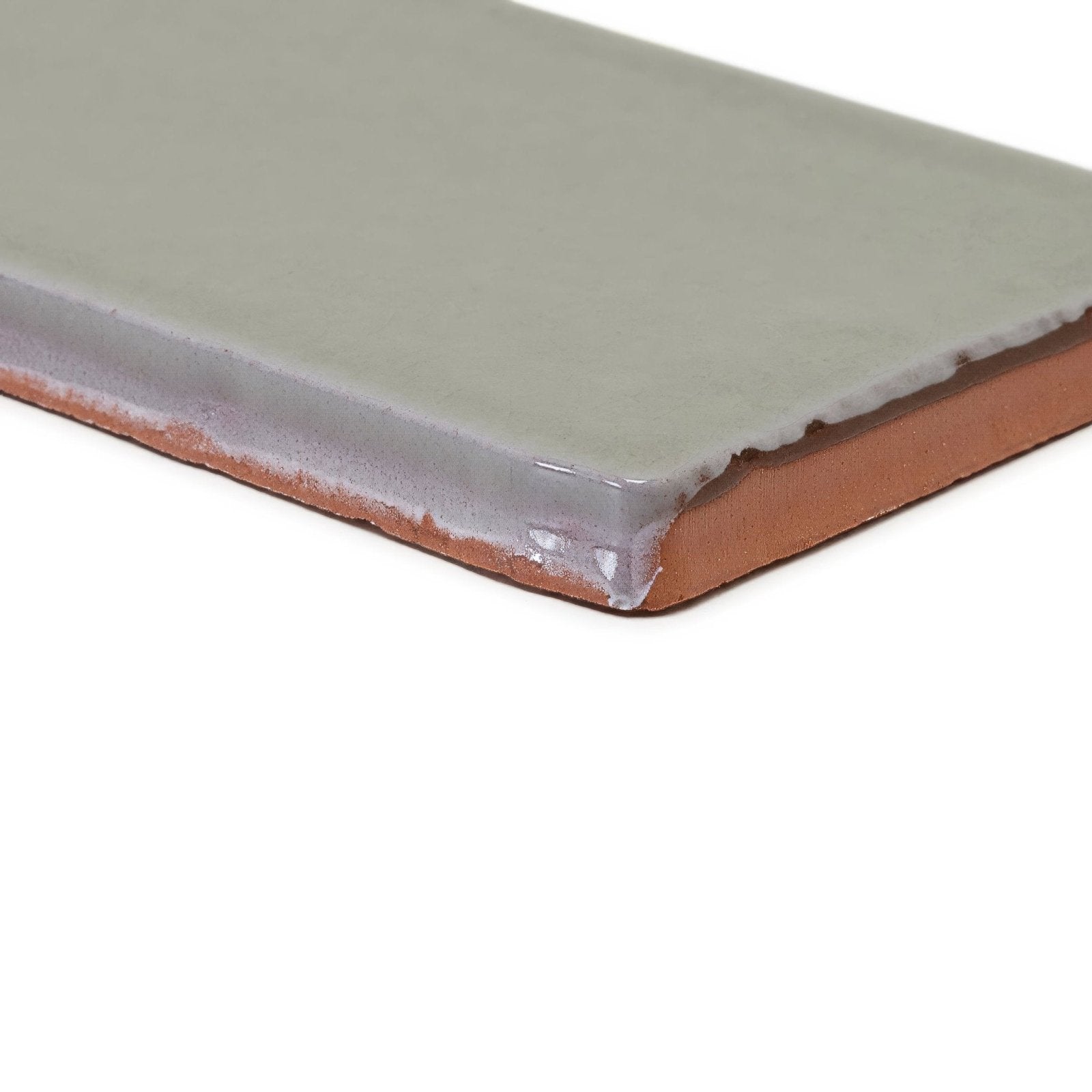 A rectangular carnival sella grey glazed tile with matte sage green glaze and exposed terracotta clay edges