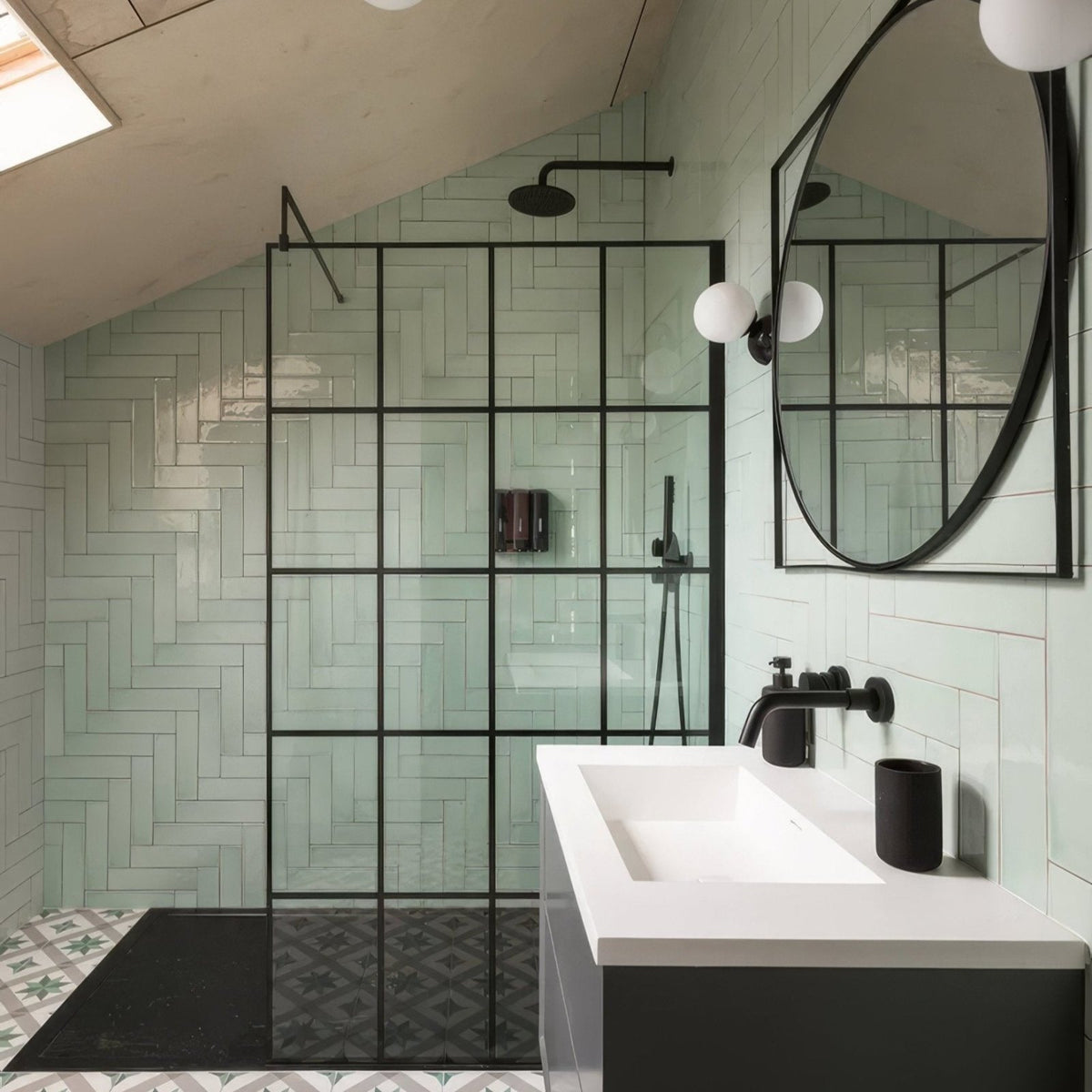 Modern black-framed glass shower enclosure featuring a herringbone pattern of light green Carter ceramic mint tiles