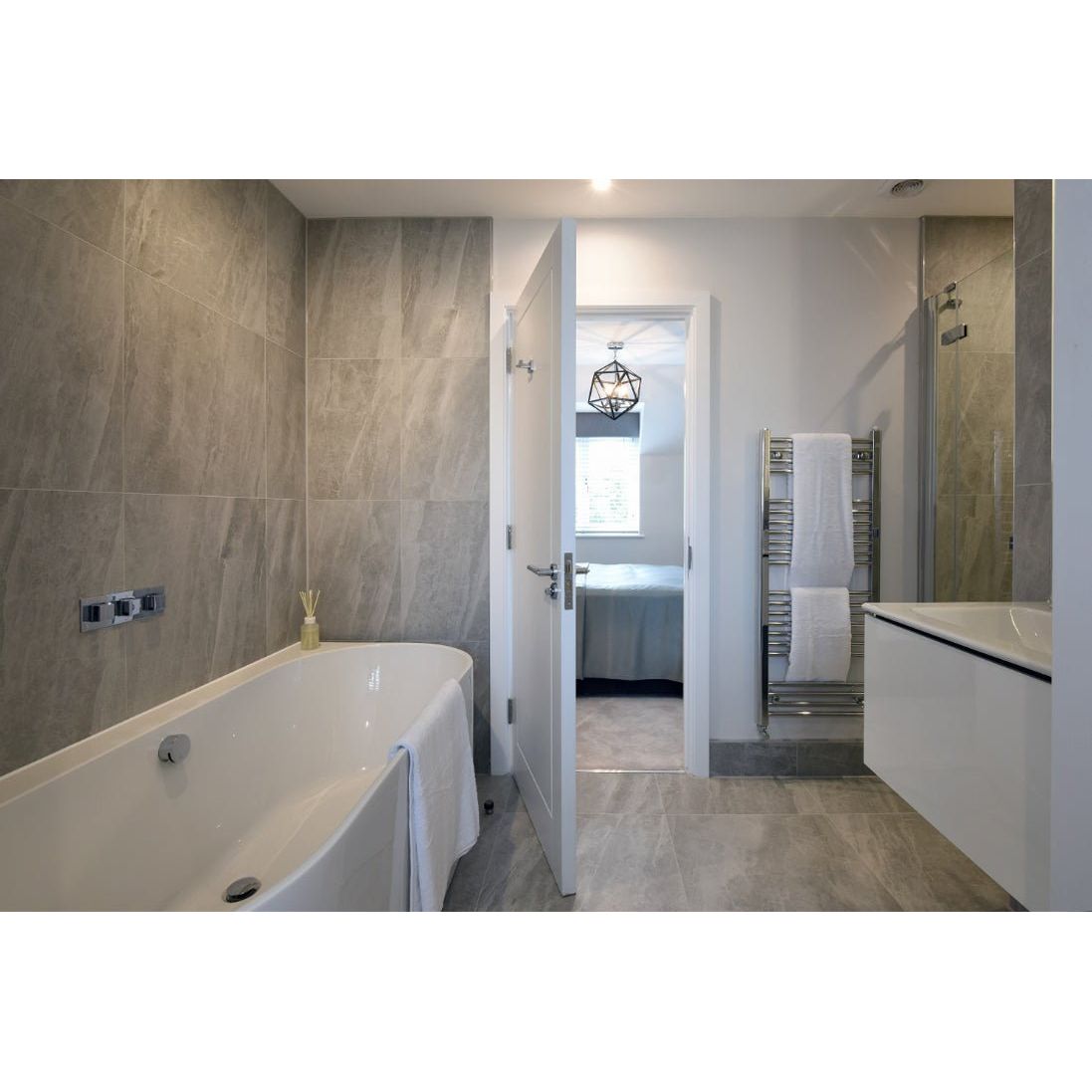 Cashmire Oyster 60 x 60cm beige marble-effect tiles with a freestanding bathtub and chrome tap