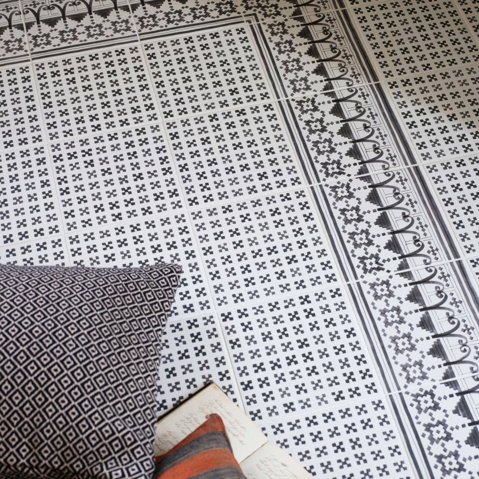 Black and white ceramic floor tiles with geometric cross pattern in casino dealer patterned border design
