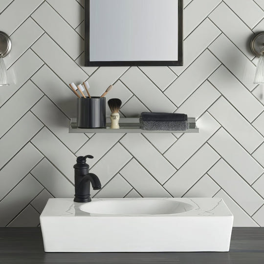 White rectangular basin with a matt black tap against a wall tiled in Chancel Grey Large Brick