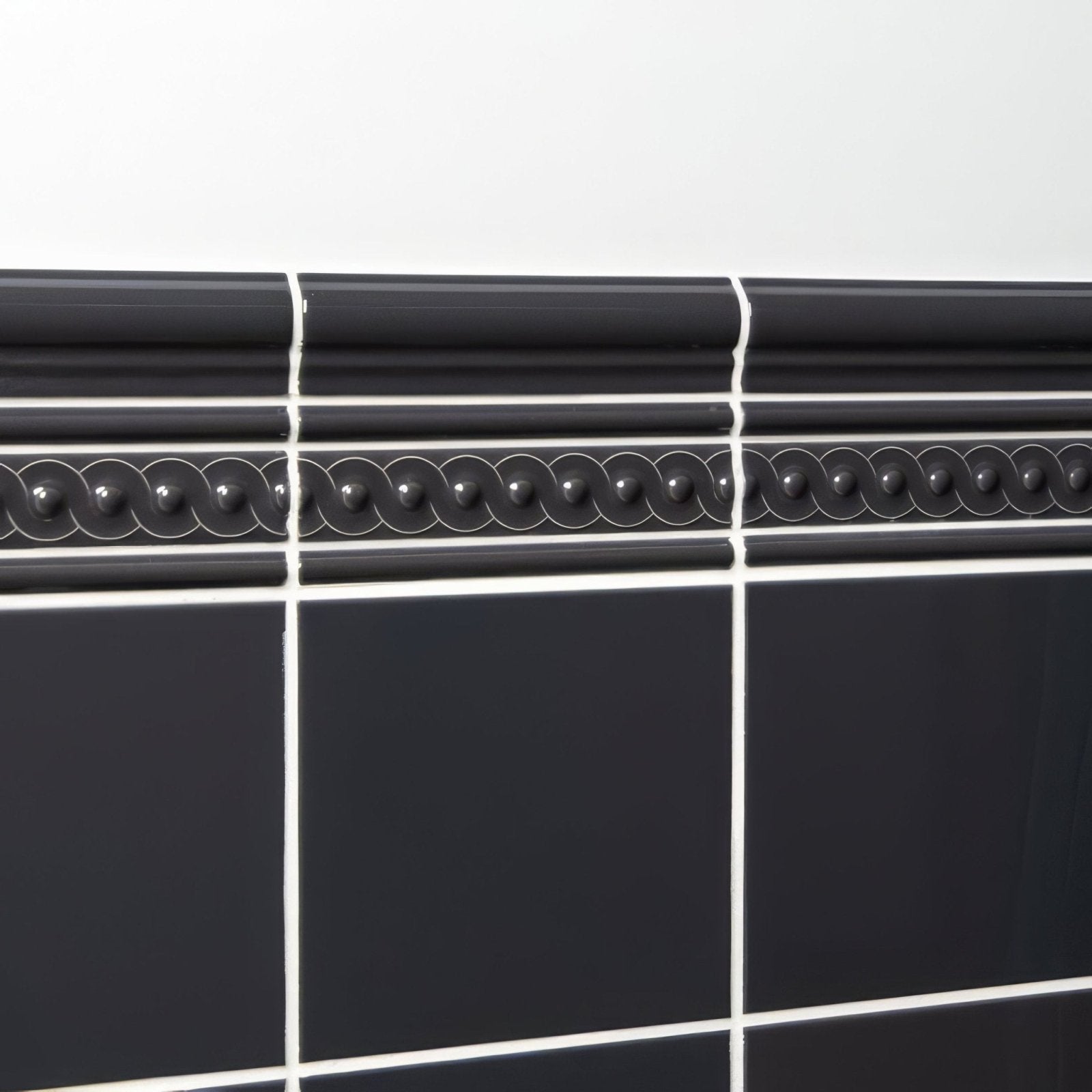 Black ceramic tile border with decorative beaded pattern and glossy finish in charcoal grey omega moulding