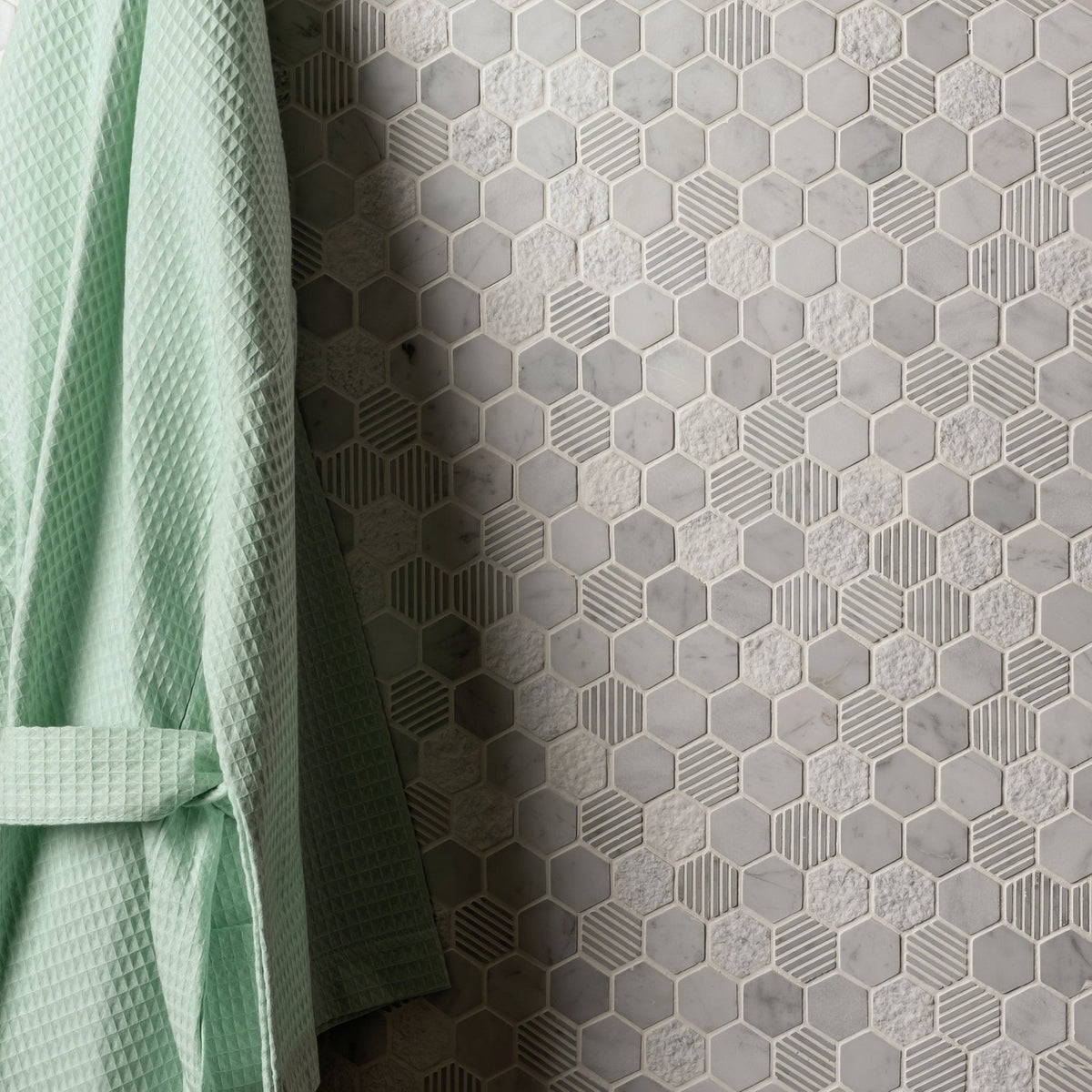 Cirrus Small Stone Hexagon grey marble hexagon mosaic wall with a light green waffle bathrobe