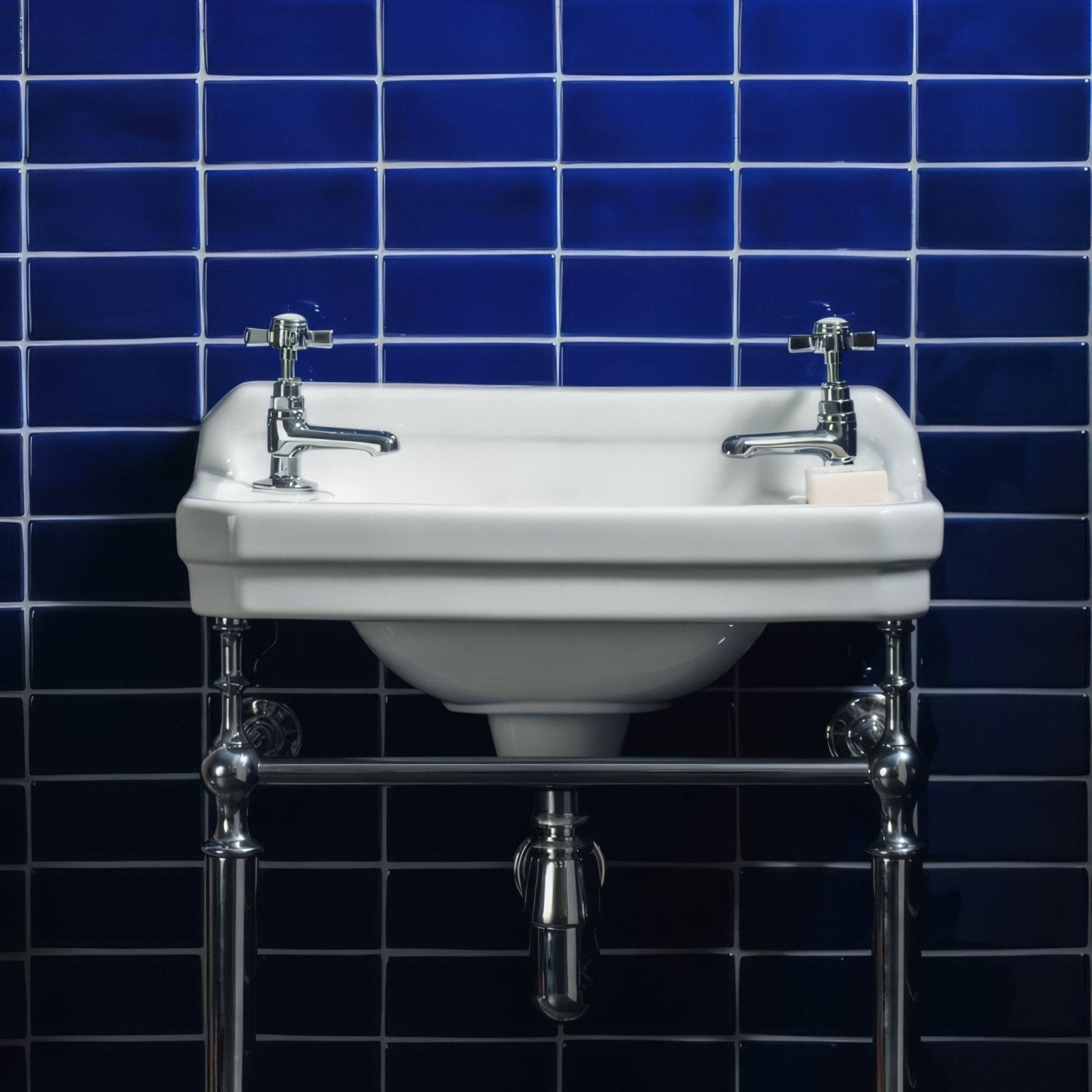 White ceramic pedestal sink with chrome faucets and plumbing in cobalt blue half tile setting
