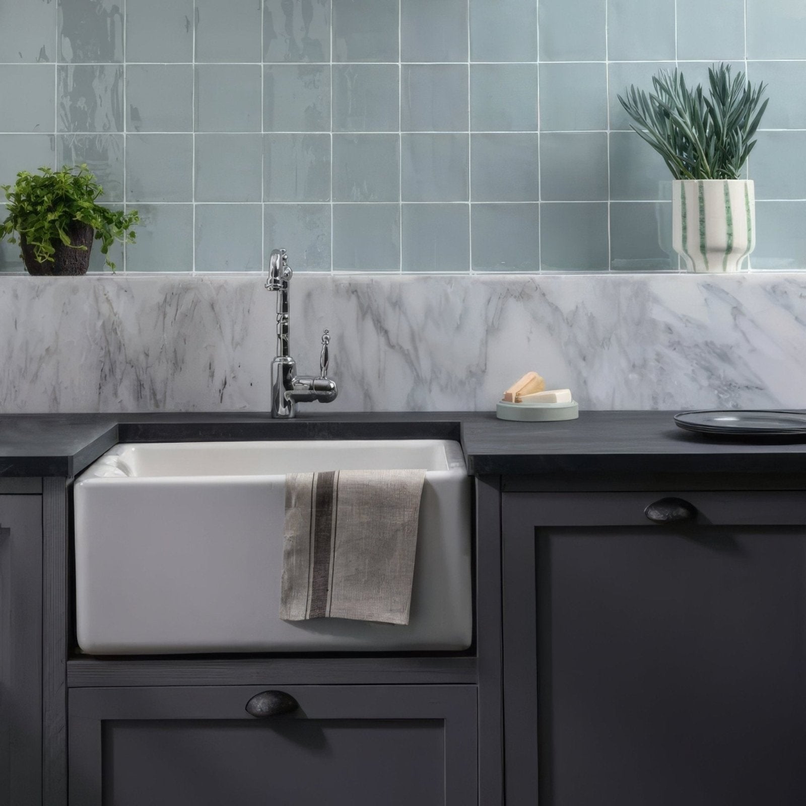 White ceramic farmhouse sink with towel draped over edge featuring blue cornflower field tile backsplash