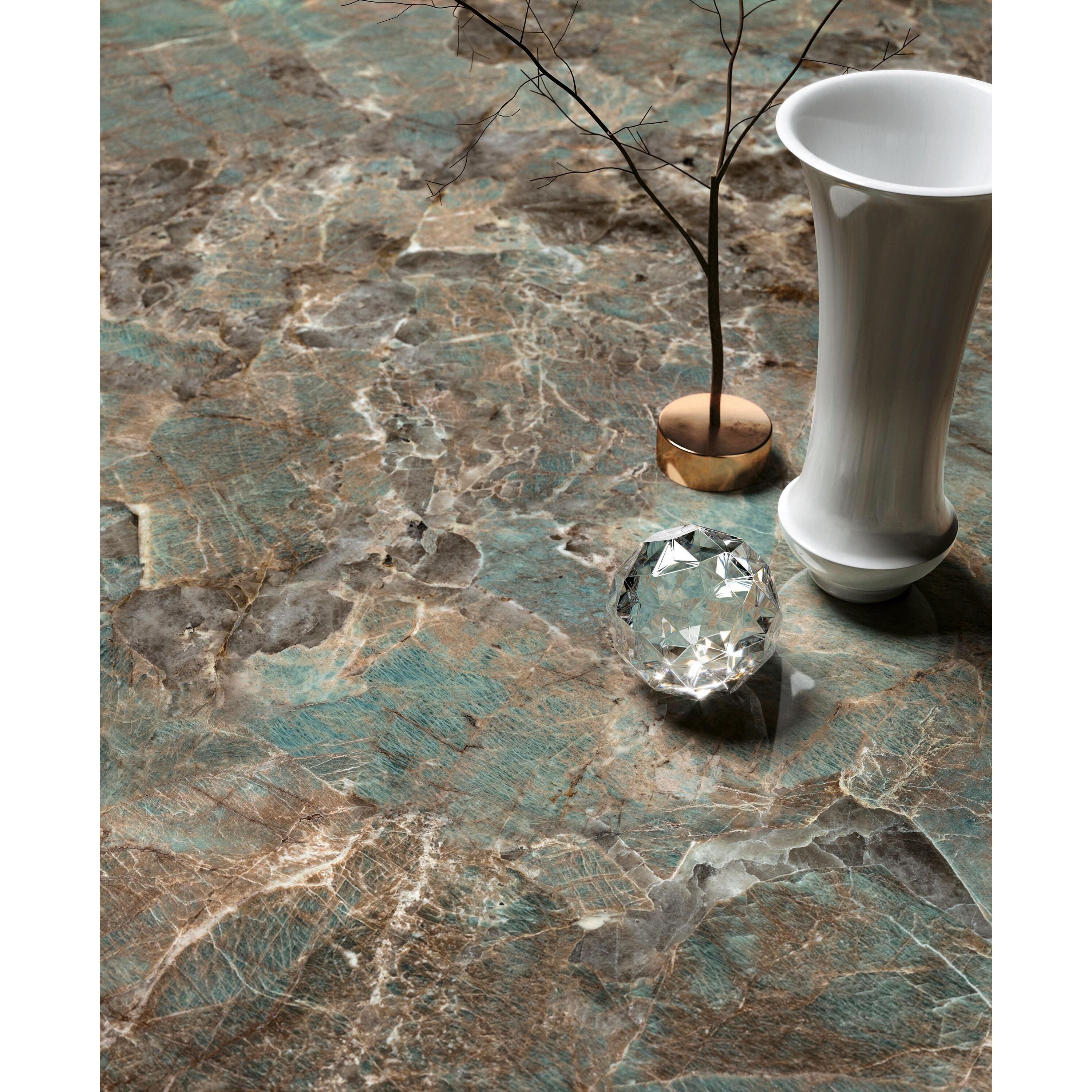 A clear faceted crystal ornament with geometric design on marble surface pairs with cosmopolitan amazzonite lappato tile