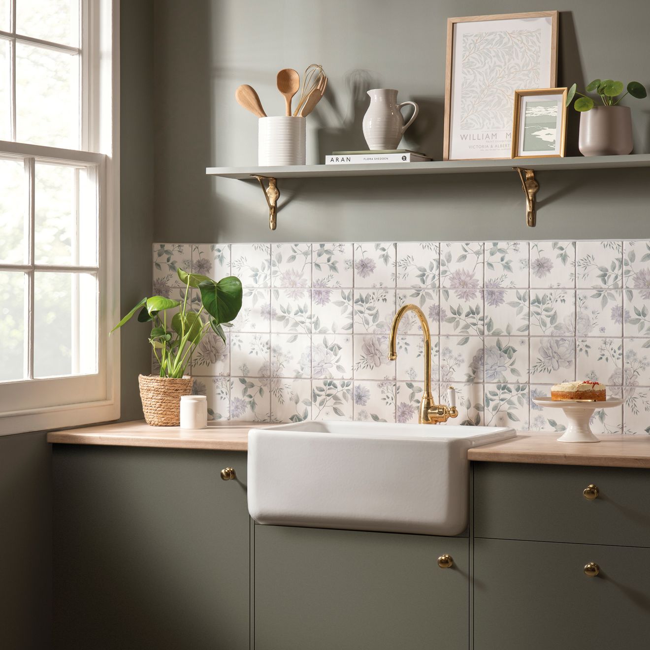 White farmhouse sink with gold faucet set into dark green cabinetry in cottage garden 16 tile panel kitchen design