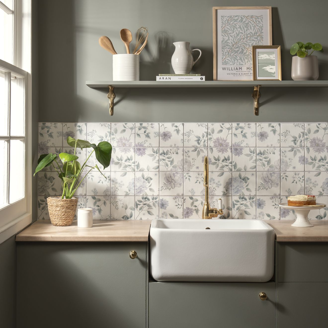 White ceramic farmhouse sink with gold faucet shown in cottage garden 16 tile panel product setting
