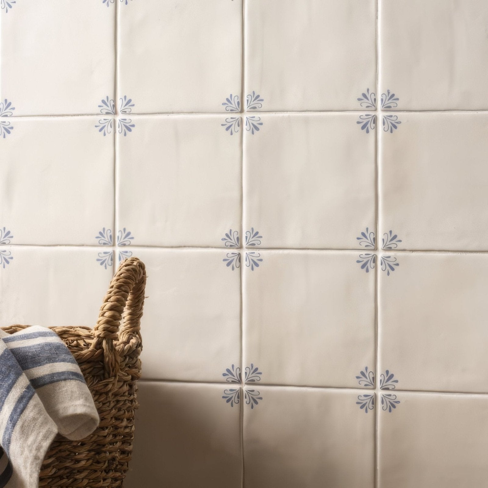 Cream-colored ceramic tiles with subtle blue floral motifs arranged in a grid pattern country delft ada
