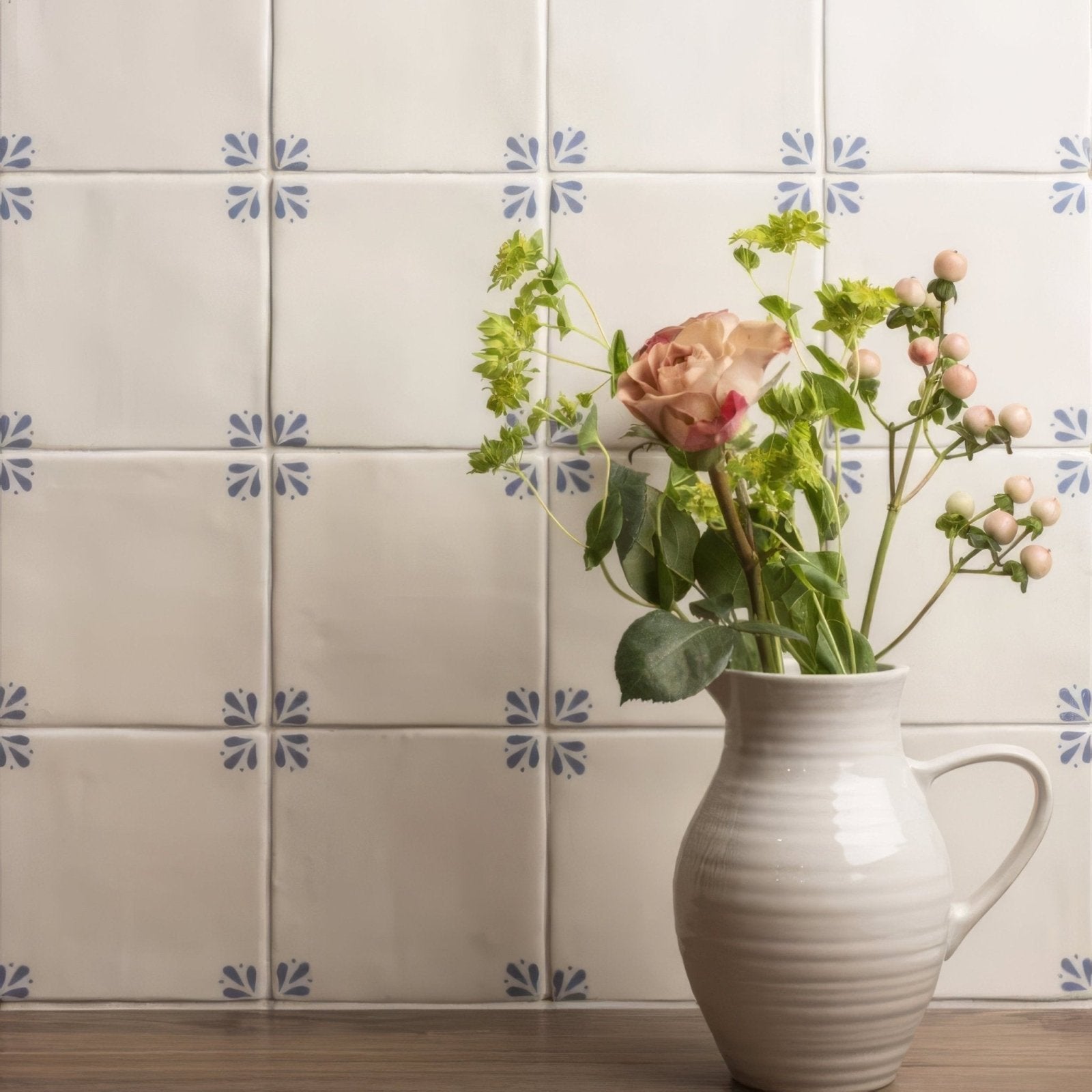 Cream-colored ceramic pitcher with ribbed texture and handle holding pink roses and greenery in country delft cornelia style