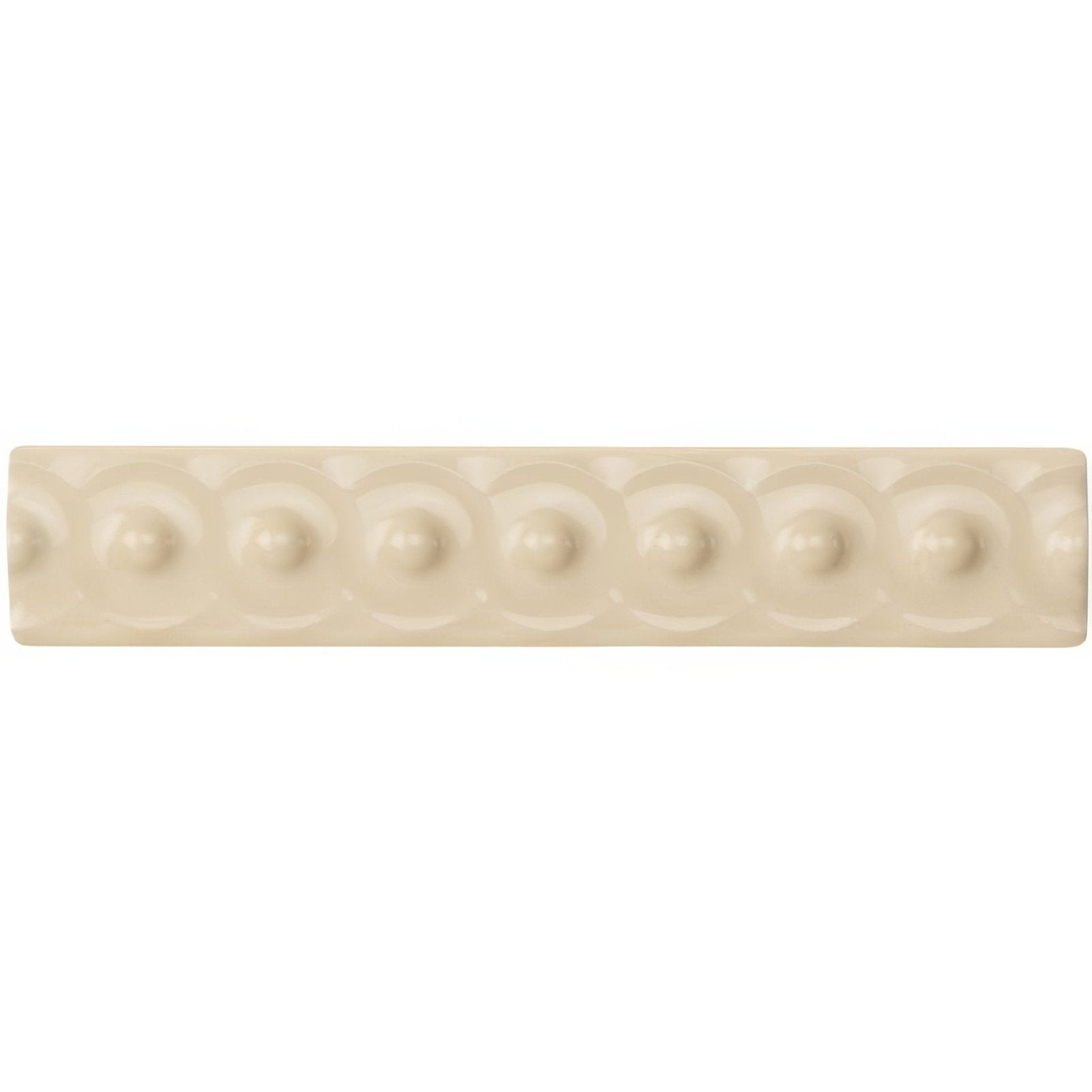 Cream-colored ceramic tile county white scroll moulding with a repeating pattern of raised circular dots