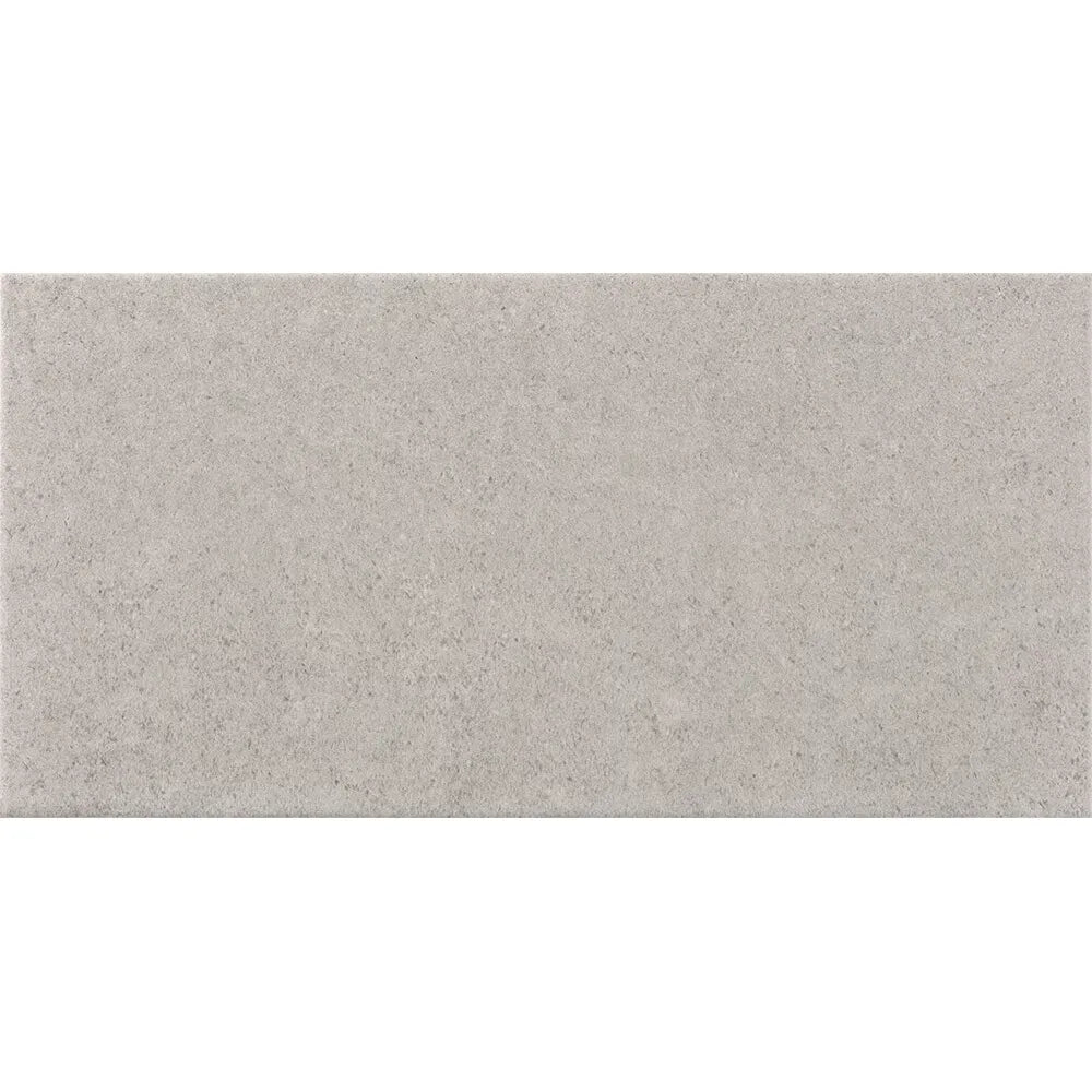A rectangular light gray ceramic tile dafne perla matt 25 x 50cm with a subtle speckled texture