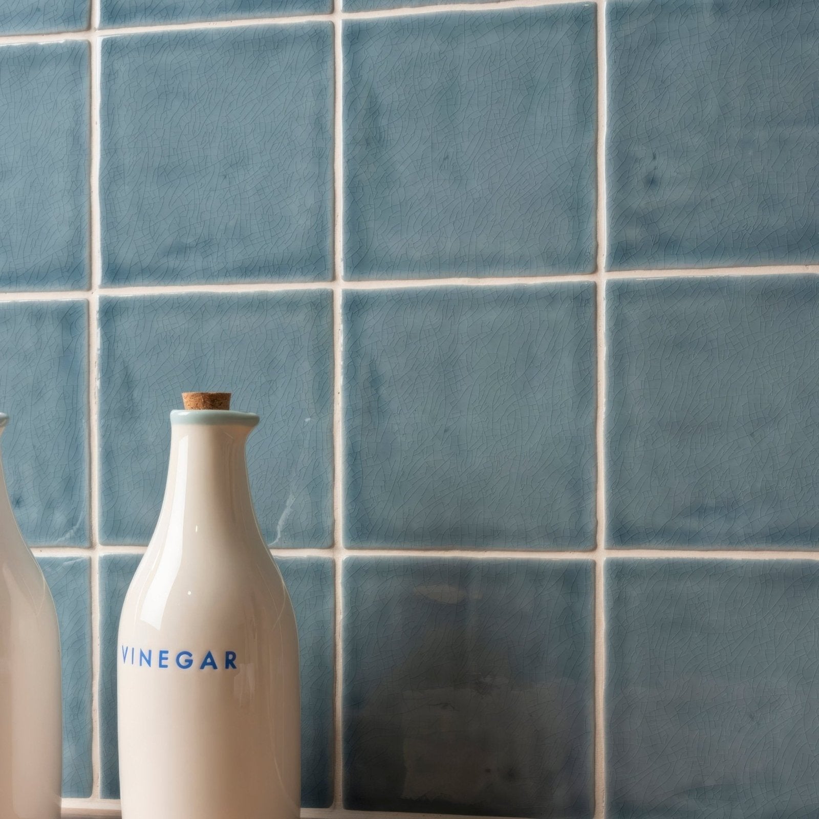 White ceramic vinegar bottle with cork stopper and blue lettering from Field Tile Danube collection