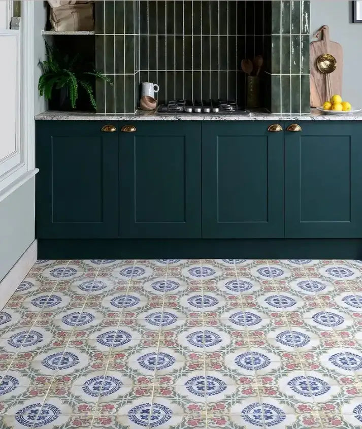 Dark green shaker-style kitchen cabinets with brass handles and a marble countertop.