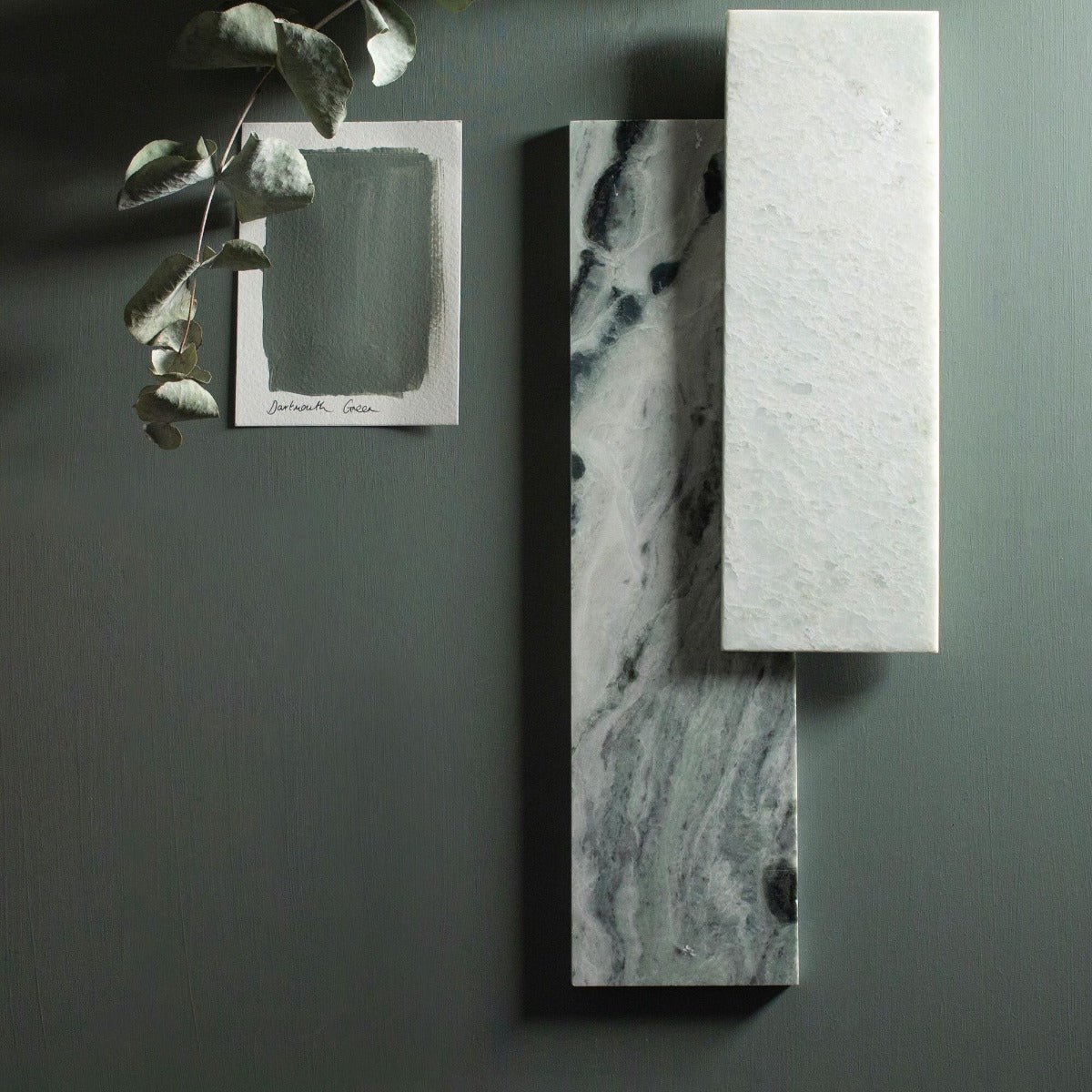 Two rectangular marble slabs in dartmouth green featuring a white base with dark veining and a solid white slab