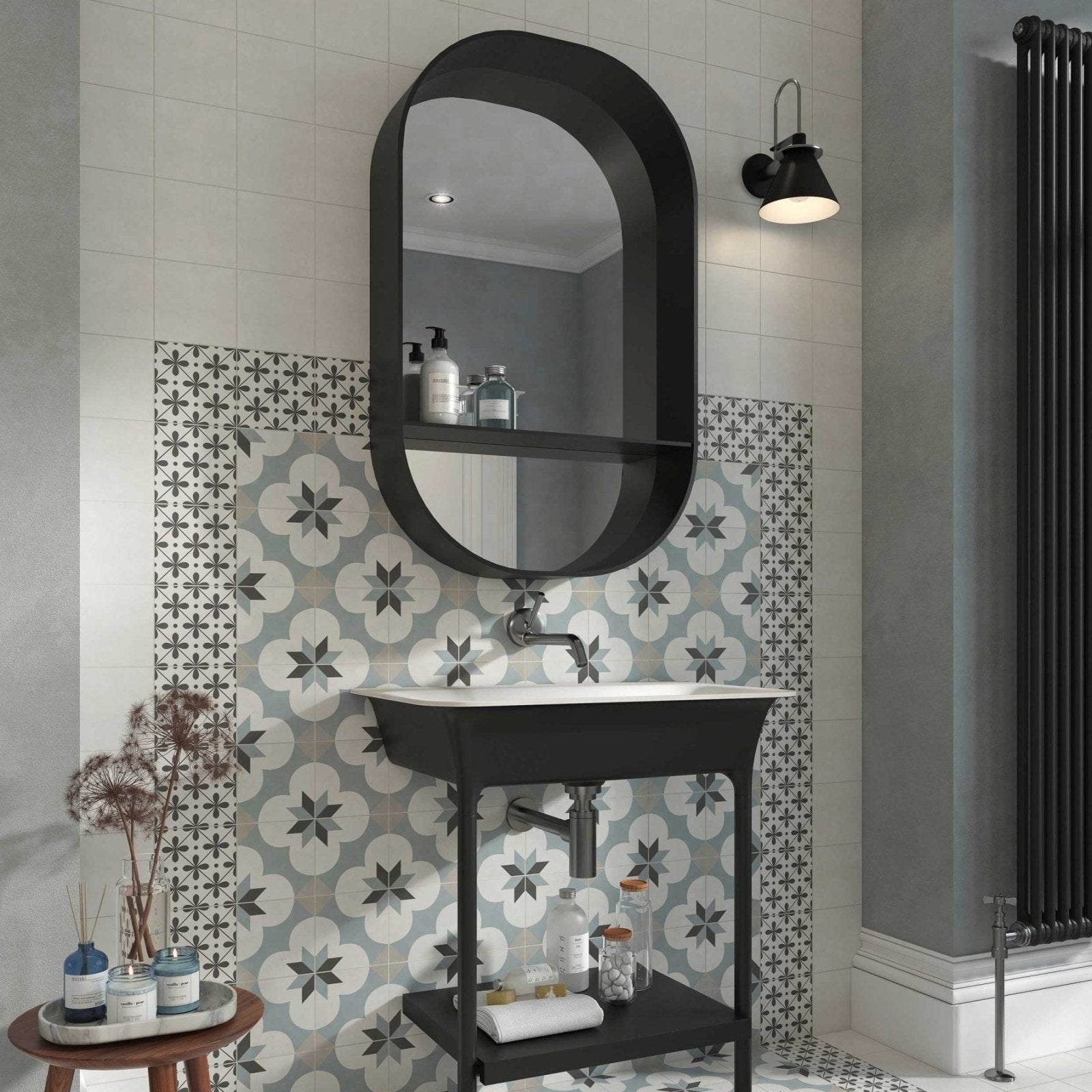 Black oval mirror with integrated shelf above white sink and black vanity base featuring decorata 09 patterned tile