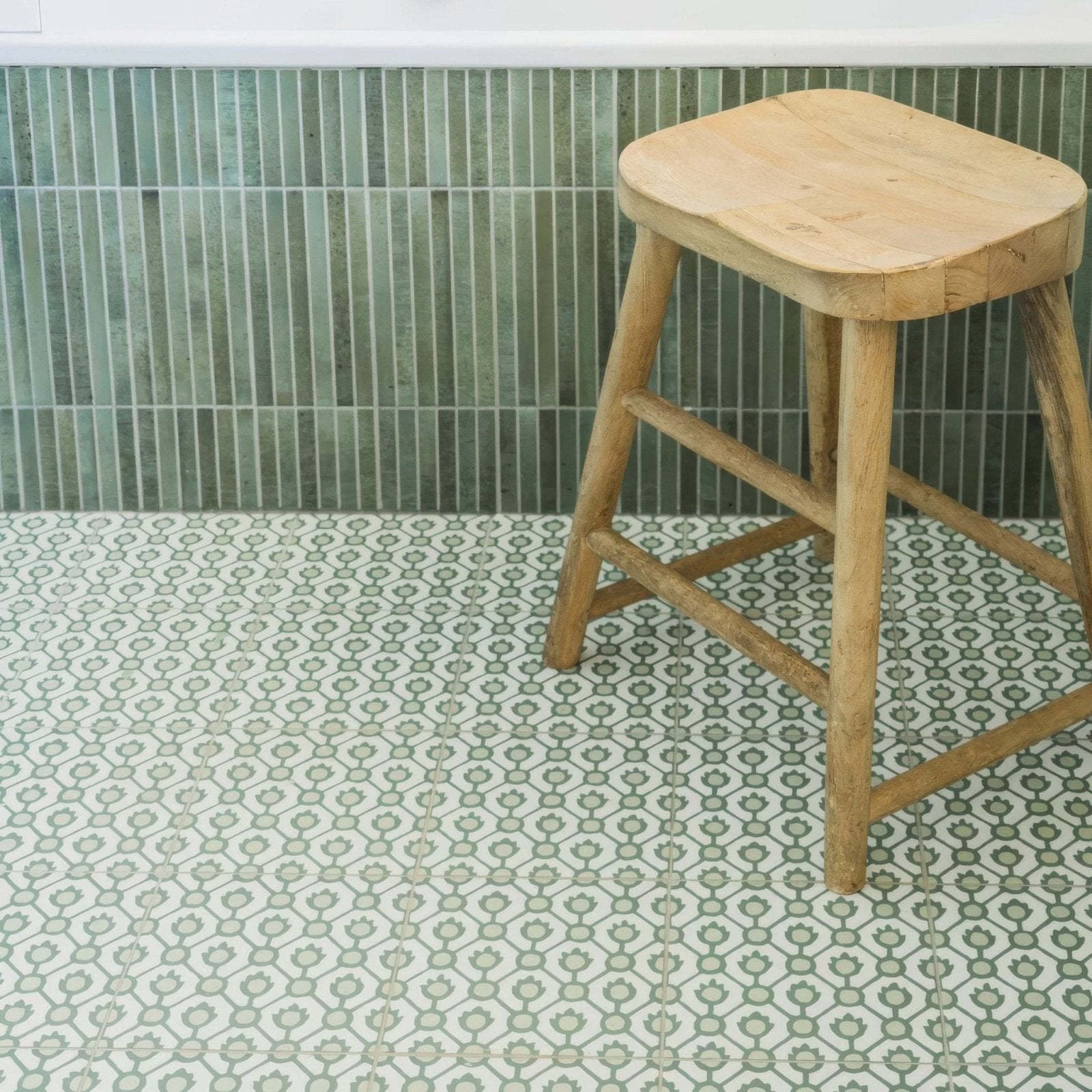 A rustic wooden stool with a natural light-toned finish and sturdy legs from Designers Guild Jaal Moss collection