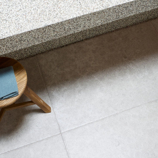 A light blue dijon natural 90 x 60cm cloth folded neatly on a round wooden stool