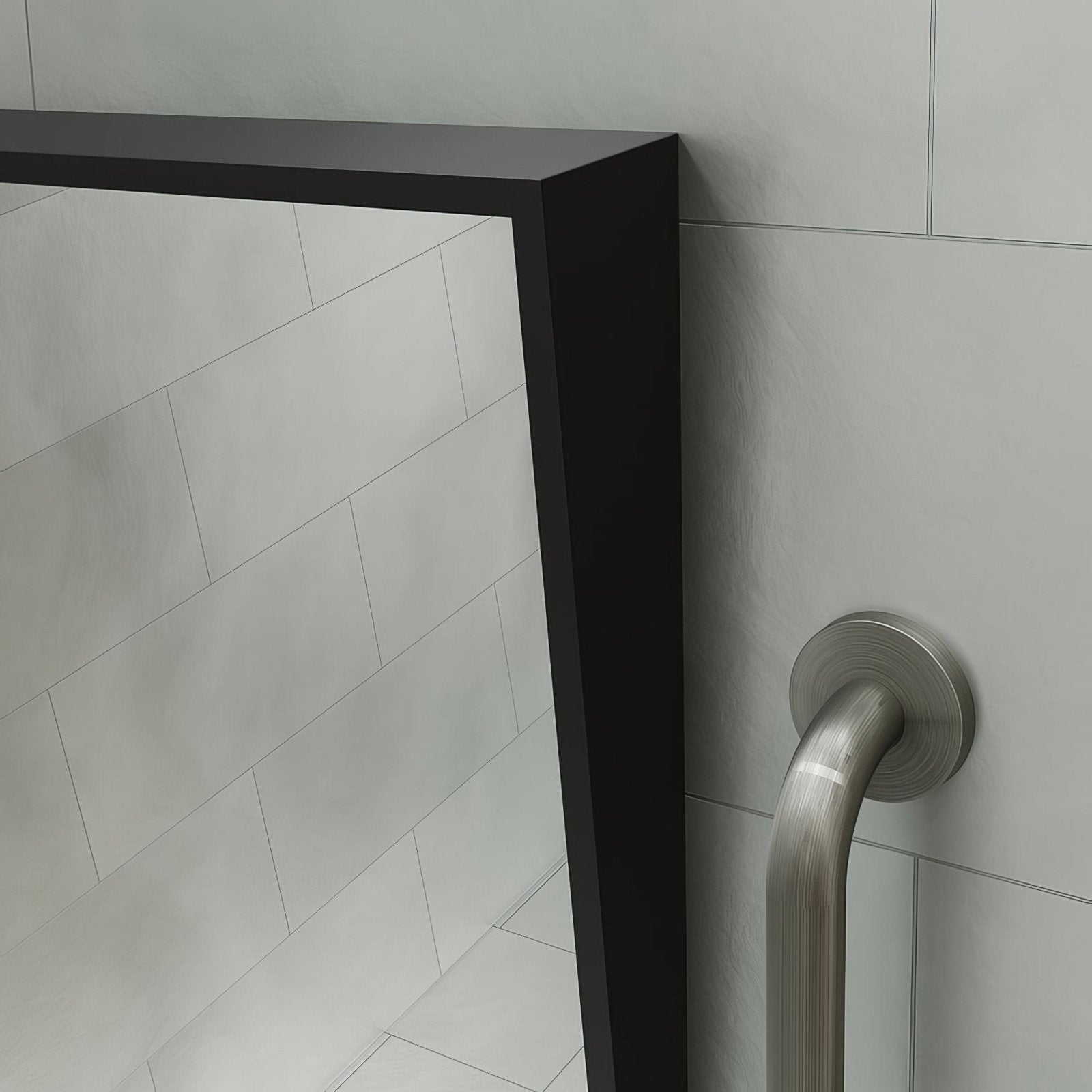 Black-framed rectangular docklands inclusive angled mirror mounted on tiled wall next to stainless steel grab bar