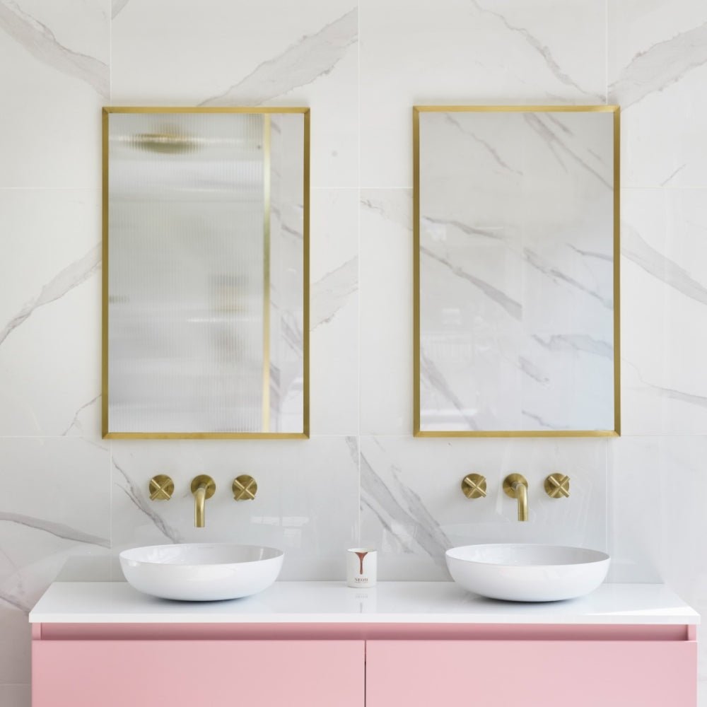 Docklands rectangular mirror 50x80cm brushed brass gold-framed above dual white vessel sinks on pink vanity