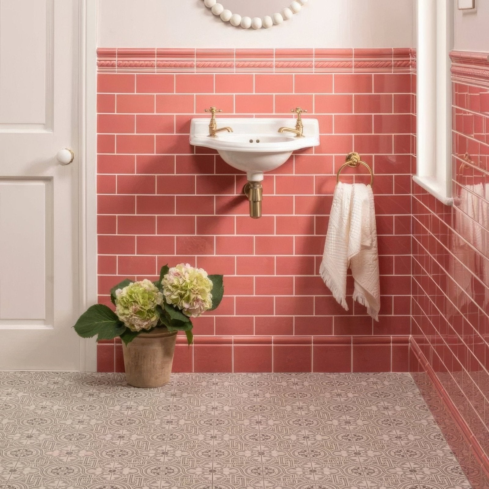 White ceramic wall-mounted duchy pink half tile sink with gold-finished faucets and plumbing features