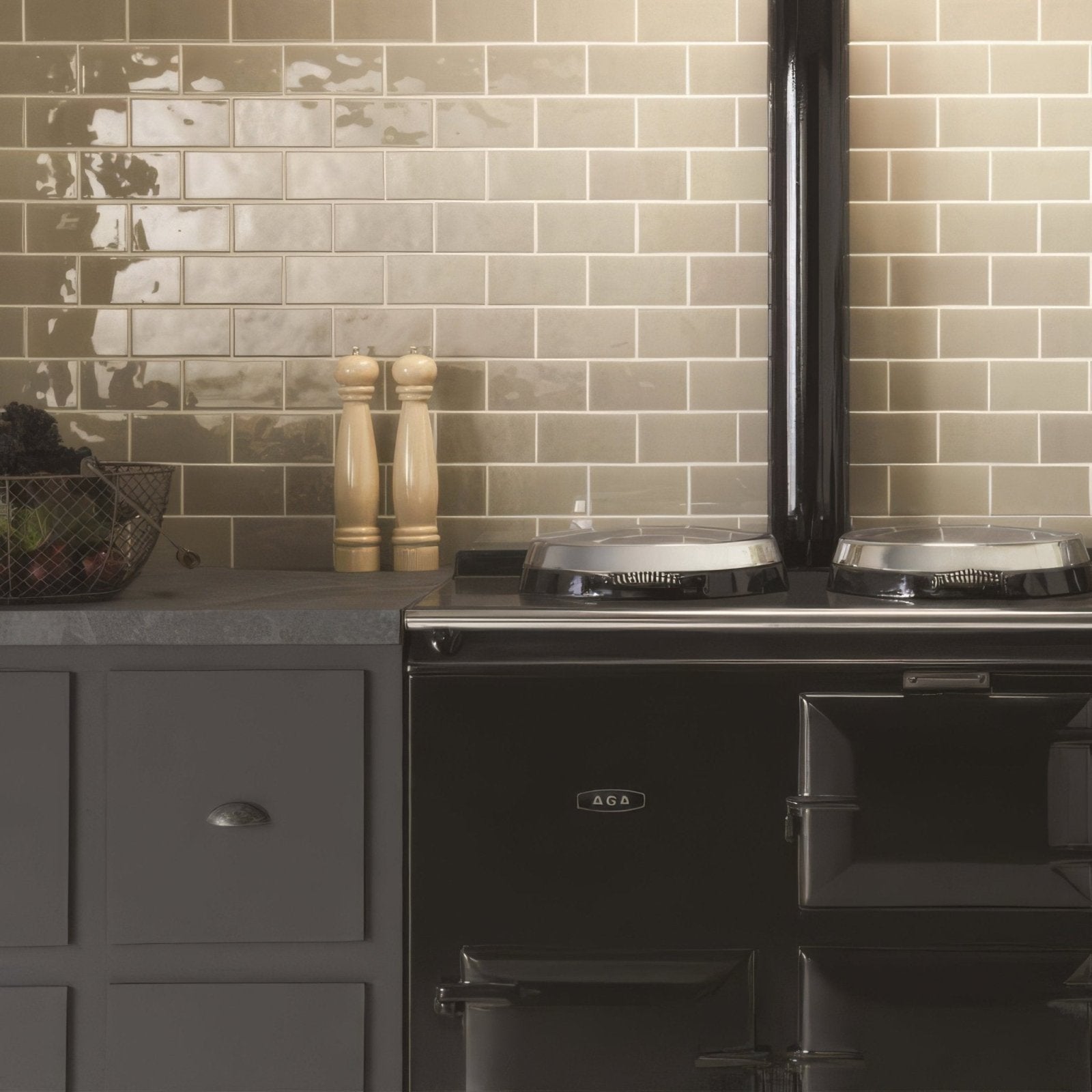 Black aga range cooker with glossy finish and two silver cooktops shown with dunwich half tile background