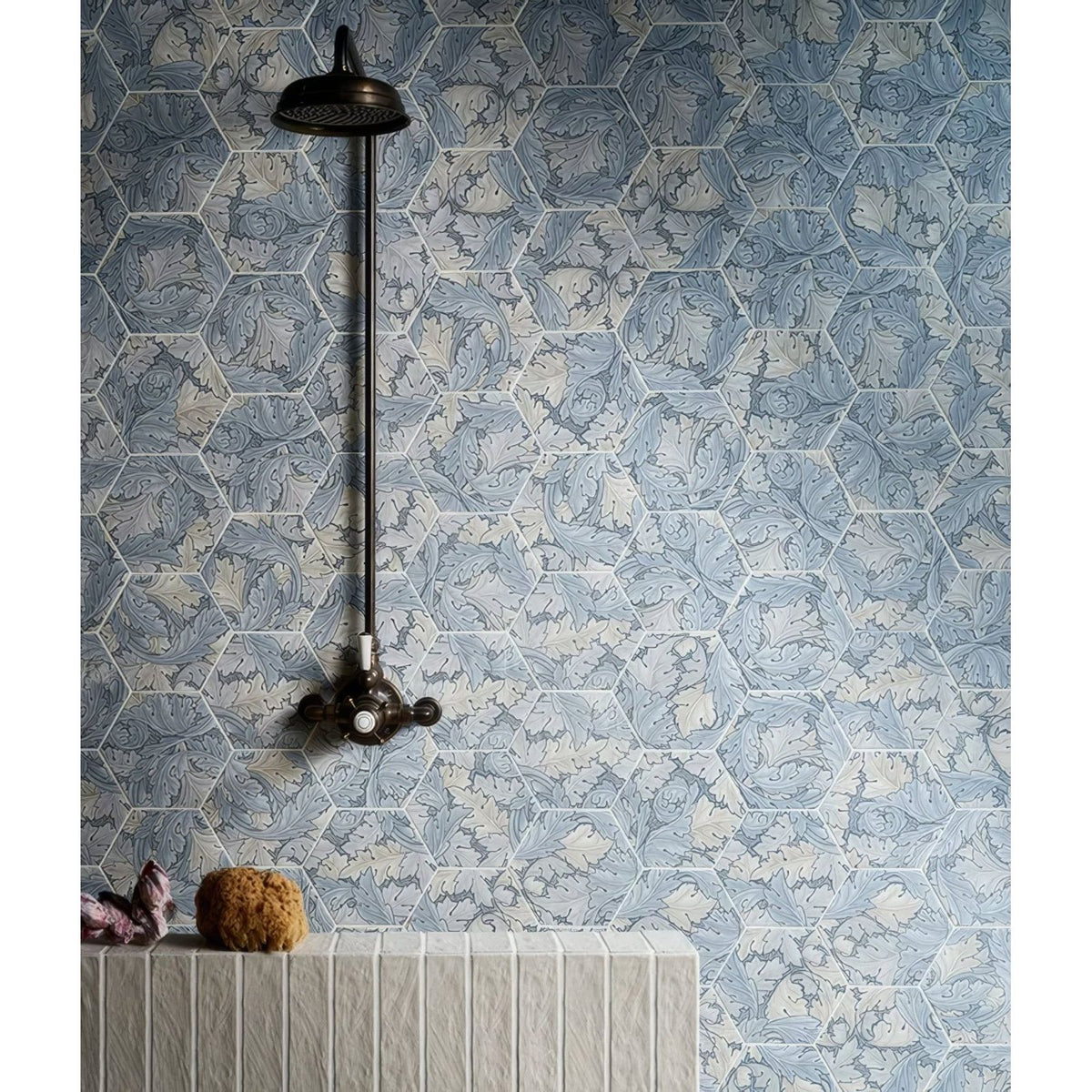 A dark bronze vintage-style earthenware porcelain linen showerhead with ornate handle mounted on blue hex tiles