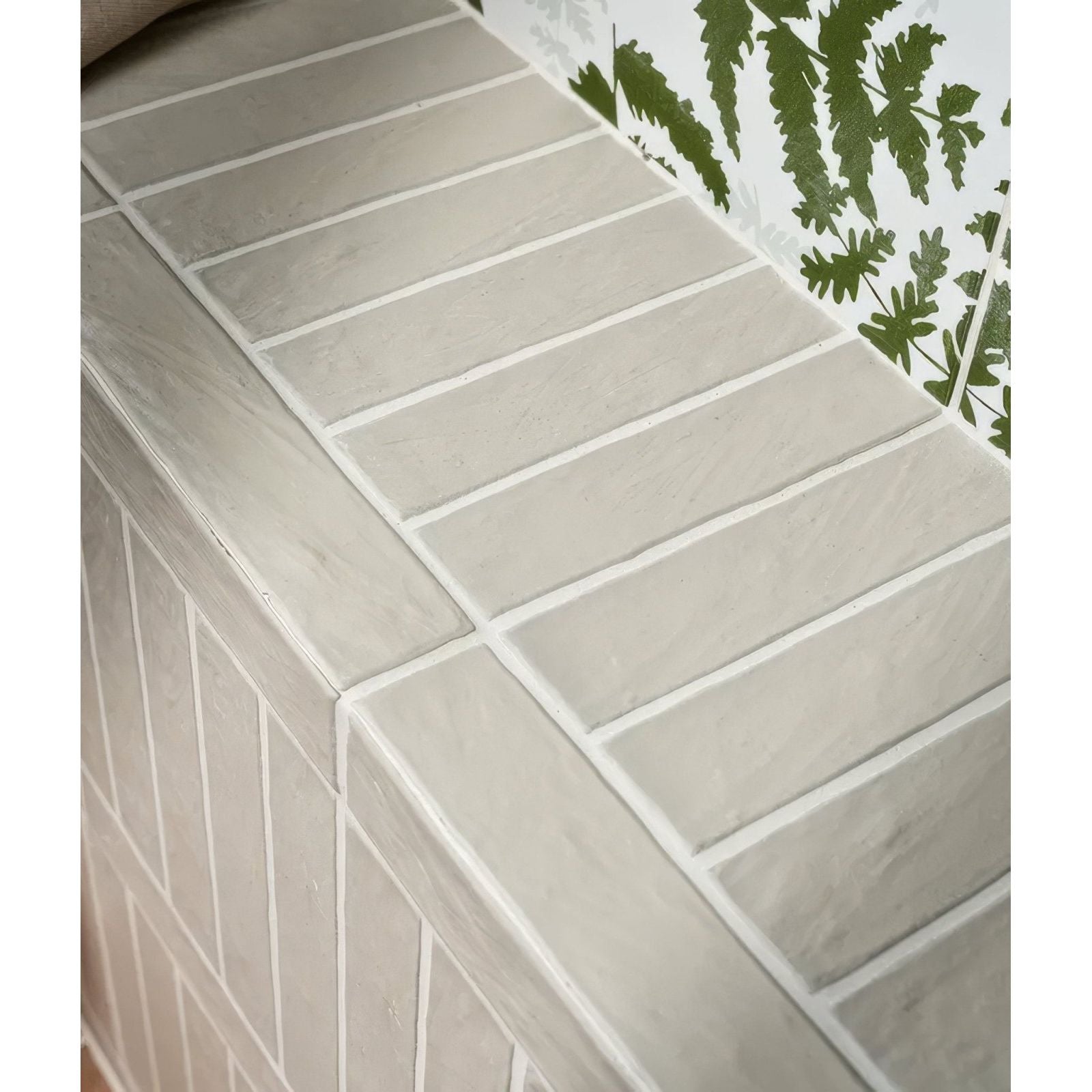 Gray rectangular earthenware porcelain plaster tiles with white grout lines arranged in a neat uniform pattern