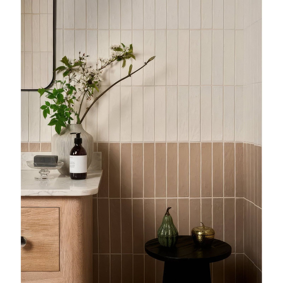 A matte gray earthenware porcelain vase with a slender neck holding white blossoms and green foliage