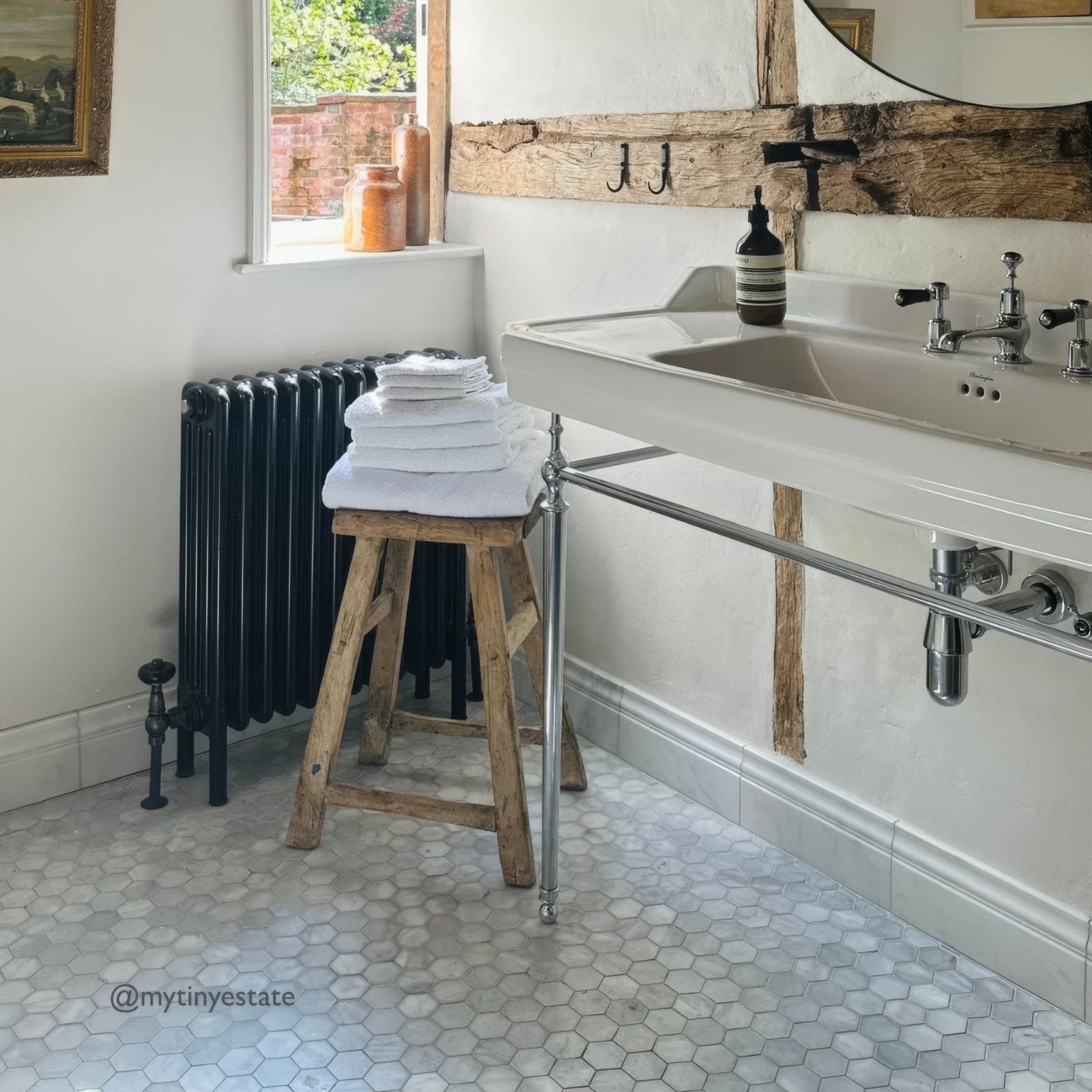 Bathroom with sink, radiator, and wooden stool with folded towels and East Hampton Large Hexagon Marble Mosaic on the floor