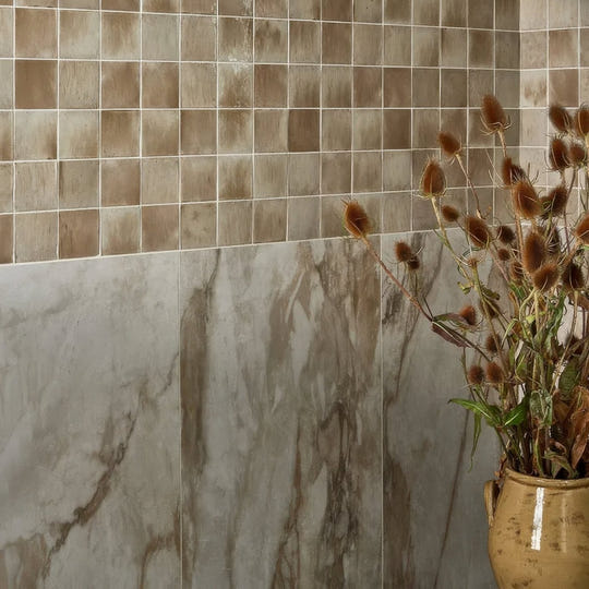 East Village Porcelain Oro 60 x 60cm cream marble-effect porcelain tile with a terracotta vase of dried thistles