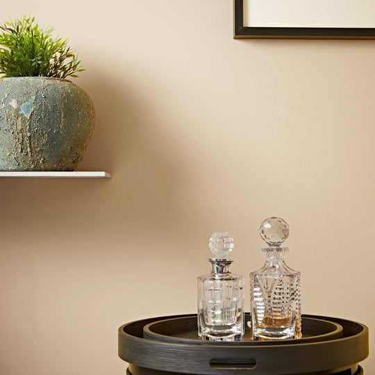 Two clear crystal ecru decanters with faceted glass bodies and spherical stoppers one with a silver-toned cap
