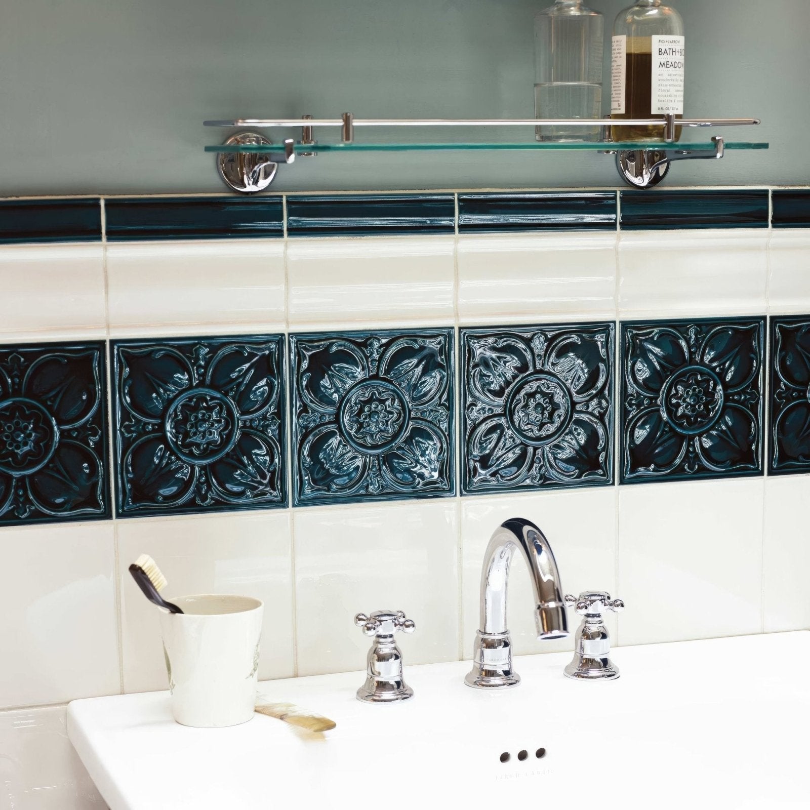 Deep teal ornate ceramic empress dado tourmaline tiles with raised floral patterns adorning bathroom wall