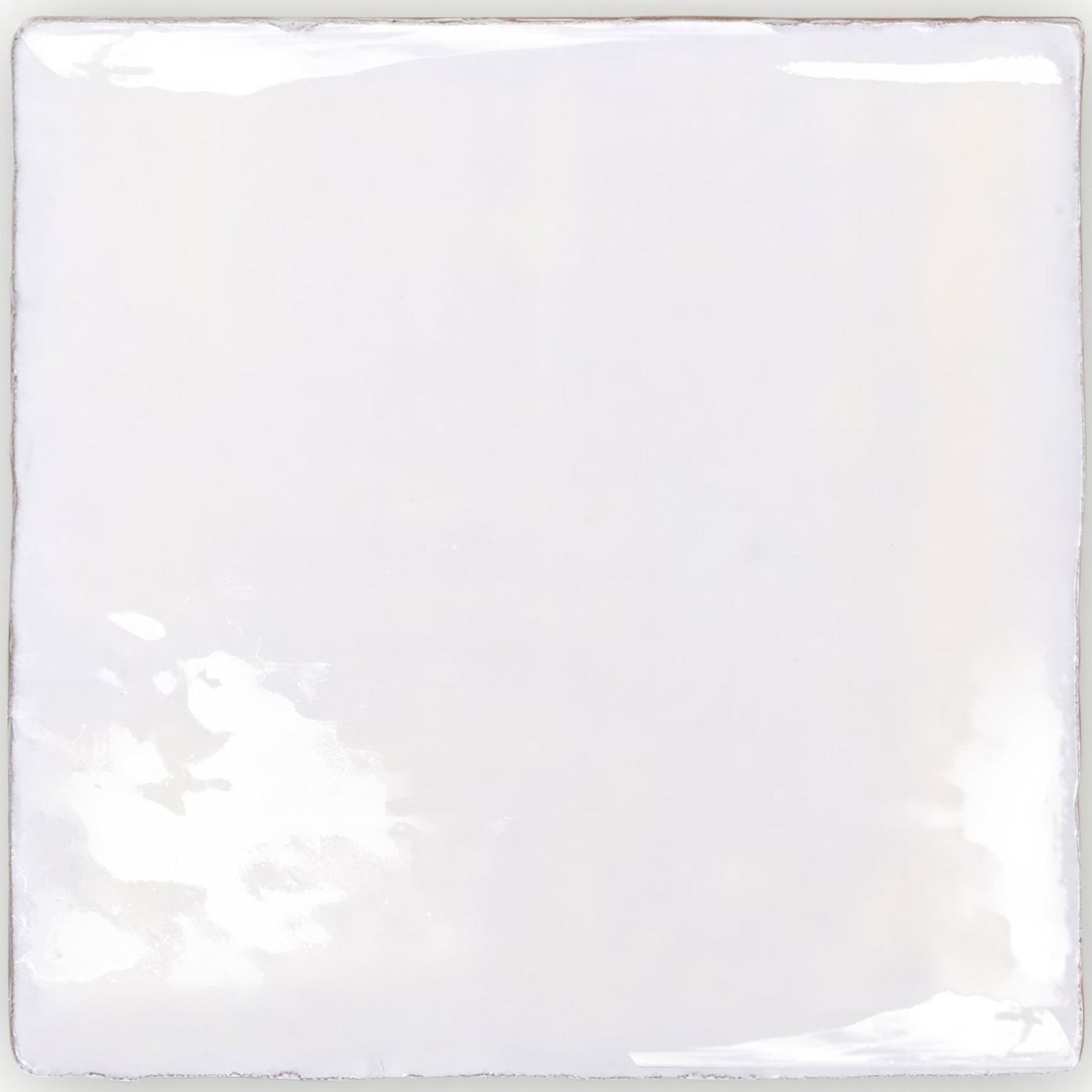 A square glossy white ceramic tile with slightly uneven edges and subtle reflections from traditional english delft base