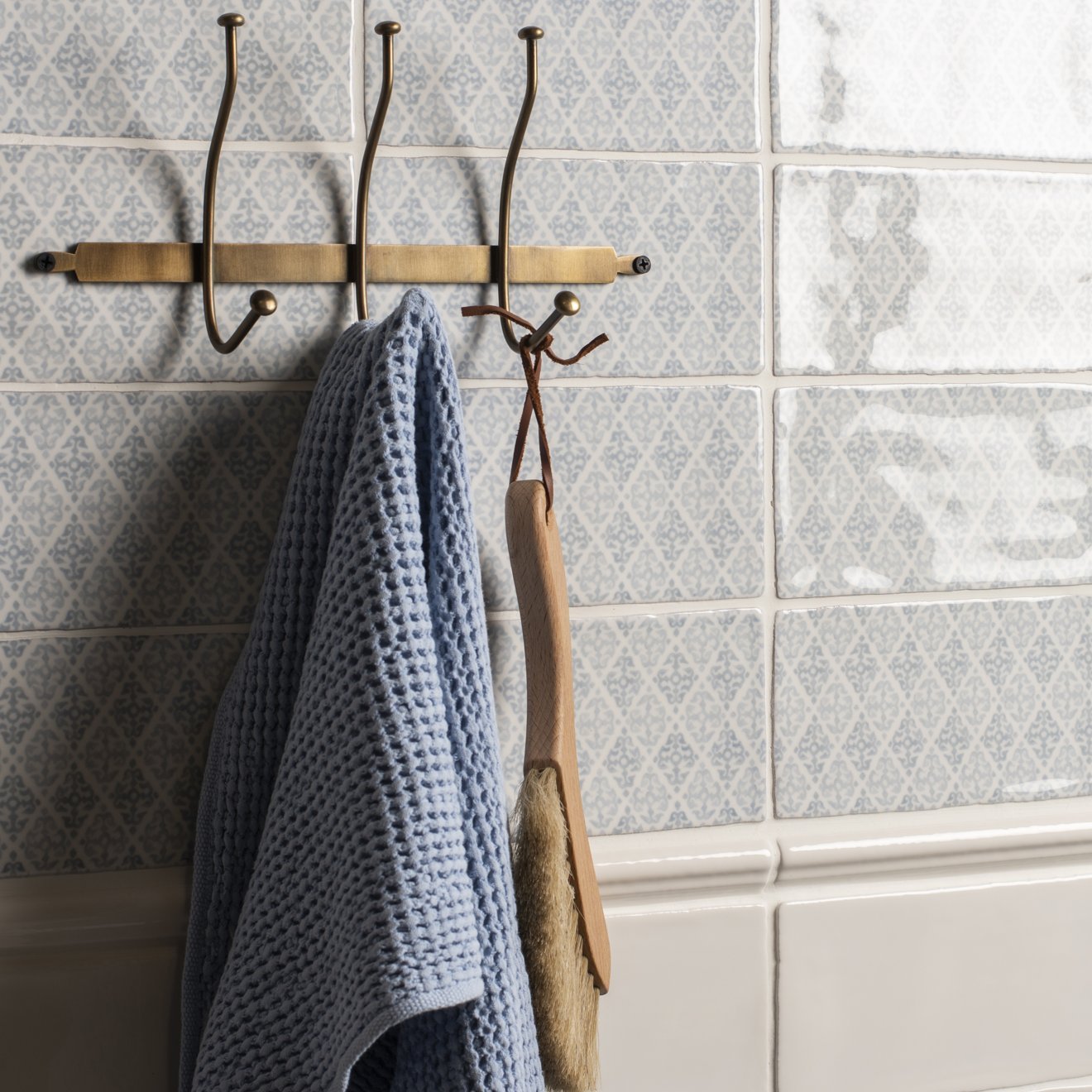 Fabrique Coraline French Blue patterned tiles with a brass towel rack and towel