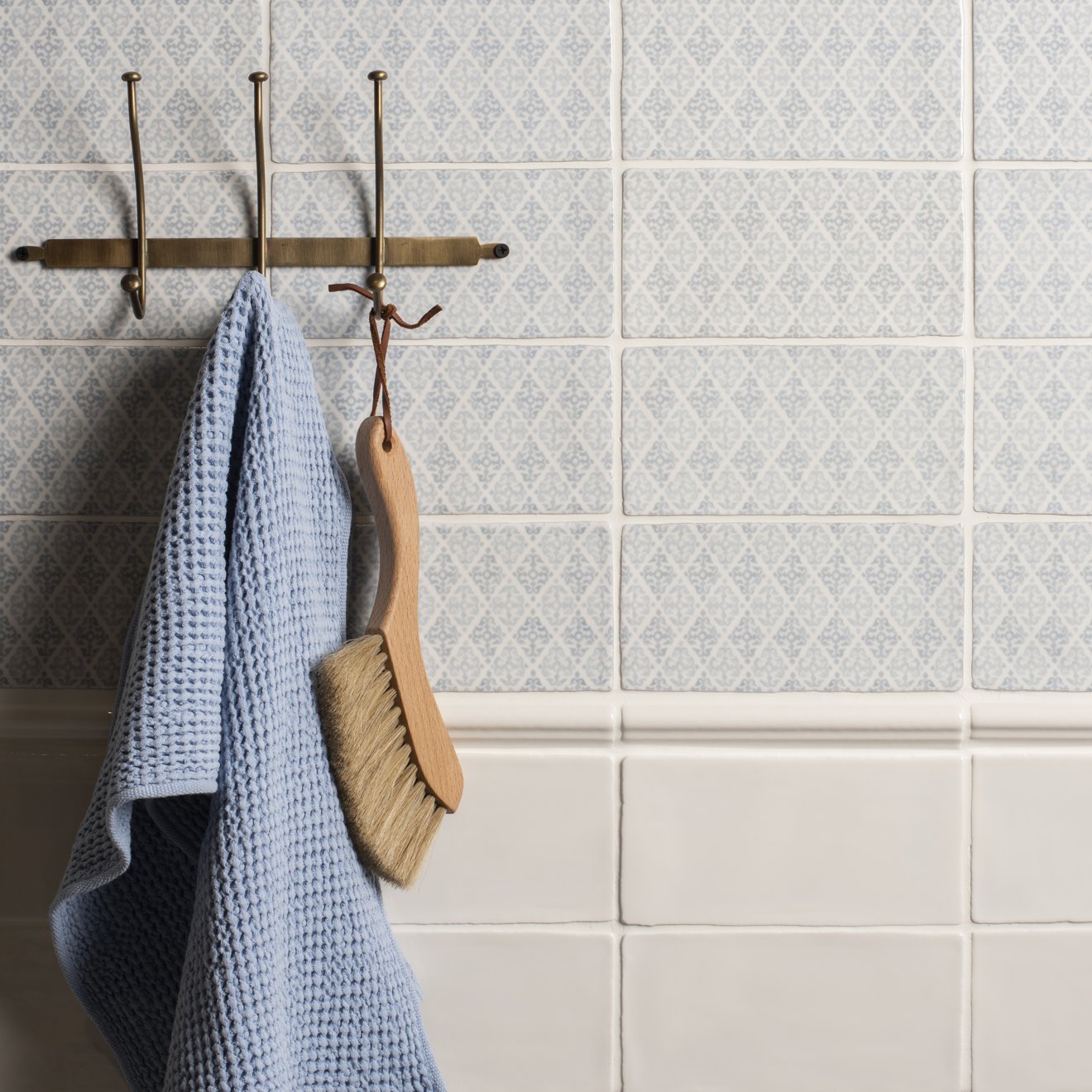 Fabrique Coraline French Blue patterned tiles with a waffle-weave towel on a brass hook
