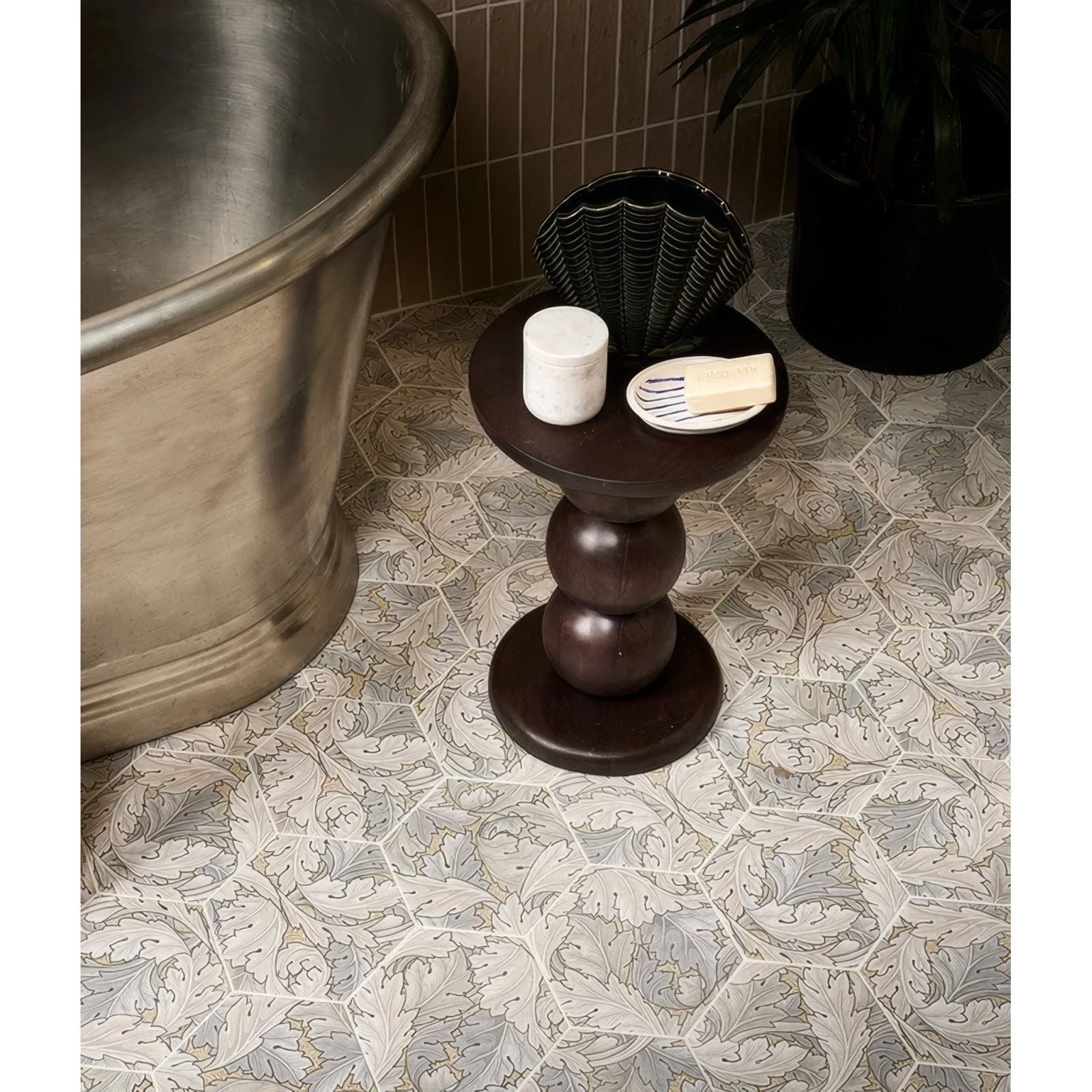 Dark brown wooden side table with a sculpted tiered base and round top folly porcelain sand matt finish